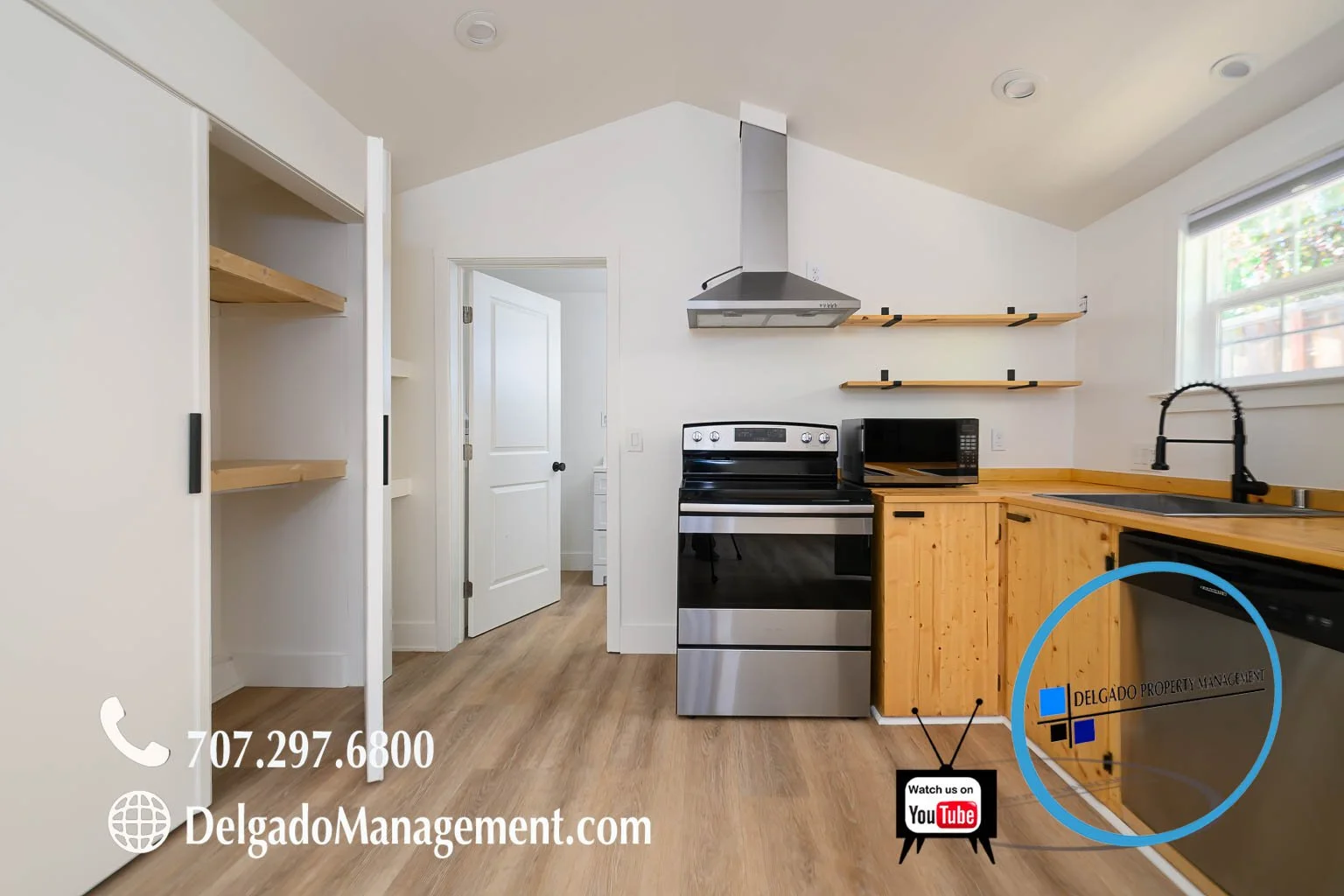 Kitchen with white walls, wood countertops, black sink, stainless steel stove and microwave, open wooden shelving, and a window with blinds.