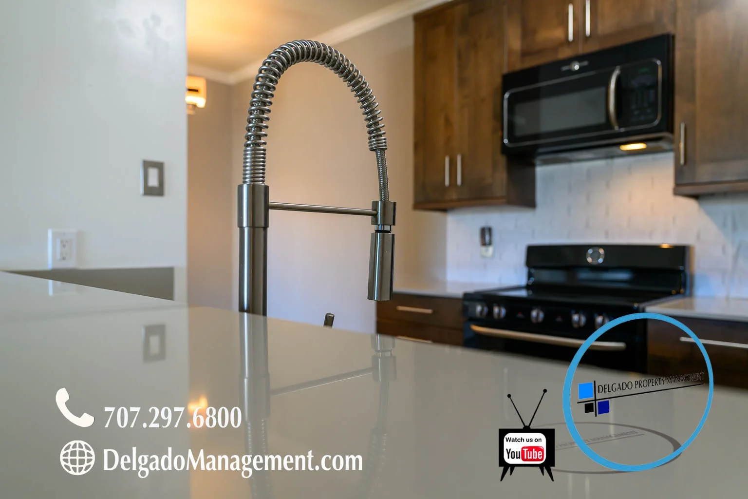 Modern kitchen with a stainless steel faucet, black oven and microwave, wooden cabinets, and branding overlay for Delgado Property Management.