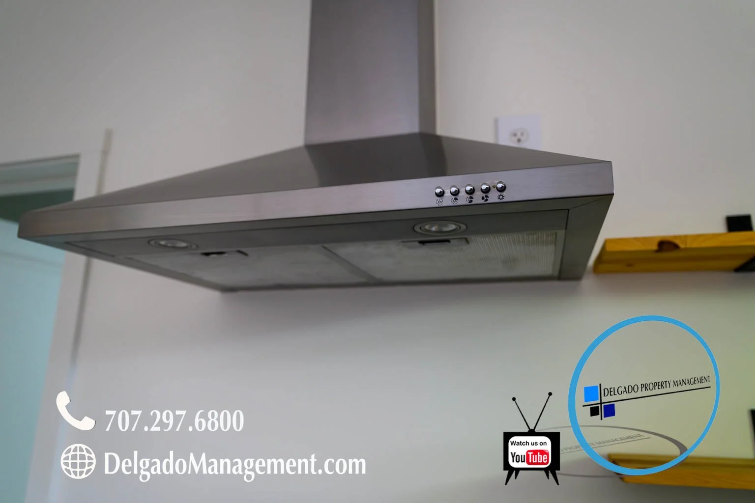 Stainless steel range hood mounted on a kitchen wall with control buttons, a light, and a vent panel.