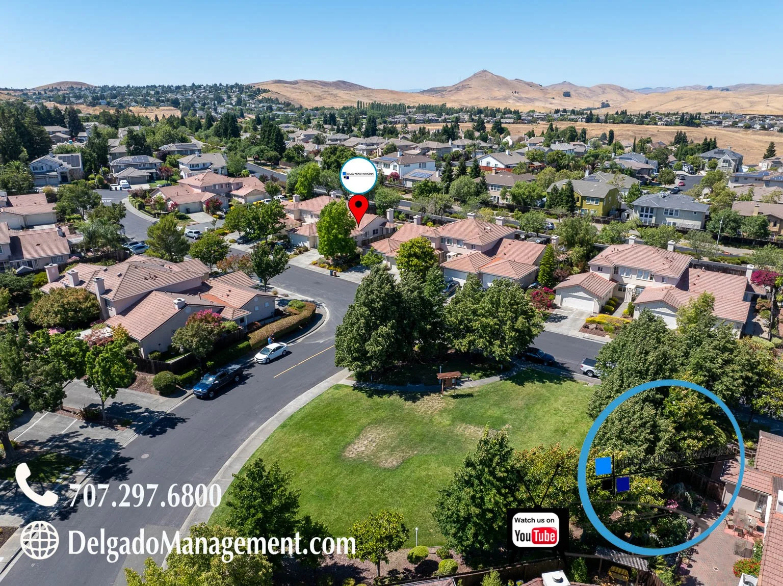 Aerial view of a suburban neighborhood with multiple houses, trees, and a park with a small pavilion, with hills in the background. There are marked locations on the image, including a red map pin and a blue circle, as well as contact information and