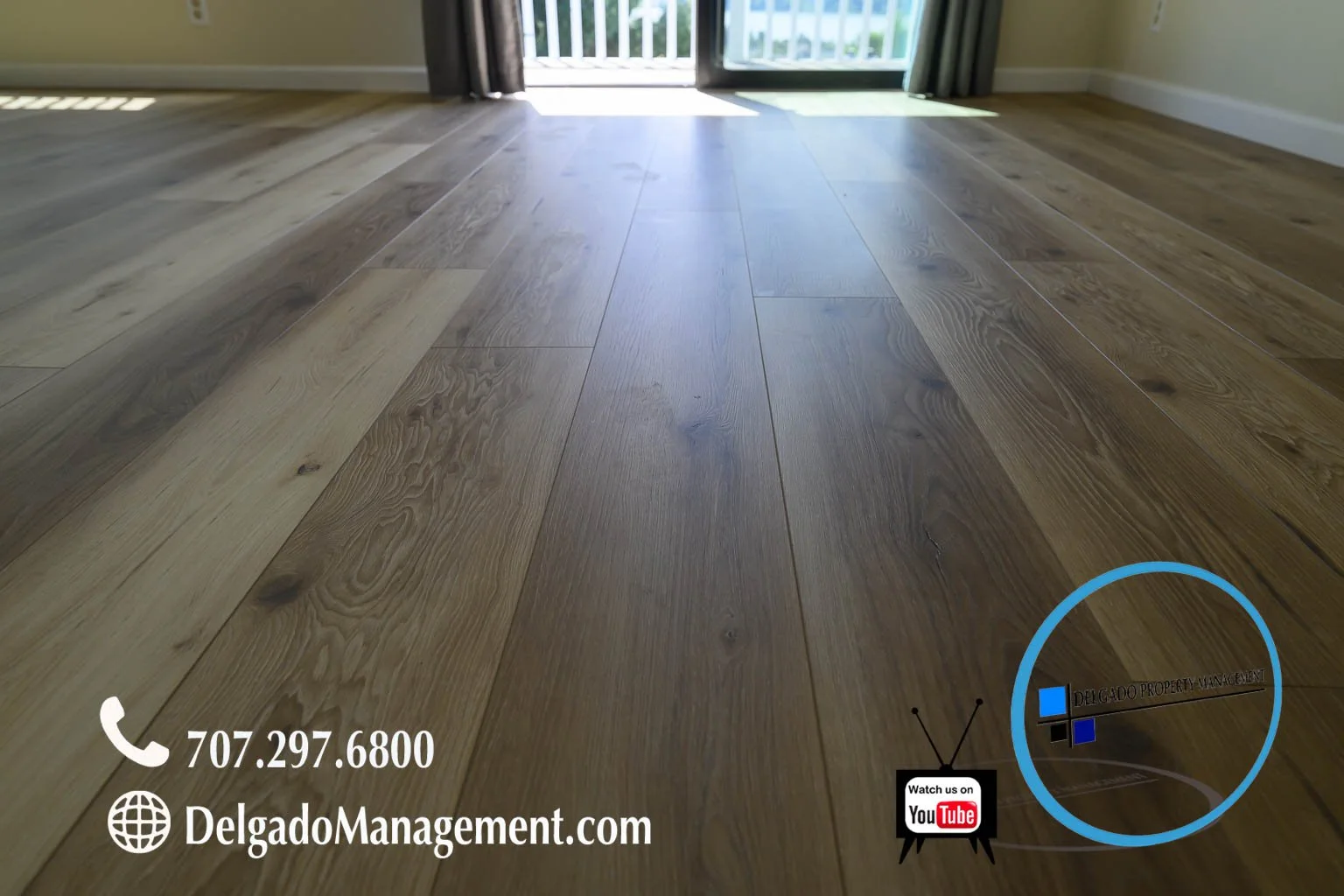 Wooden floor near a sliding glass door leading to a balcony, with a contact number, website, and YouTube icon overlay.