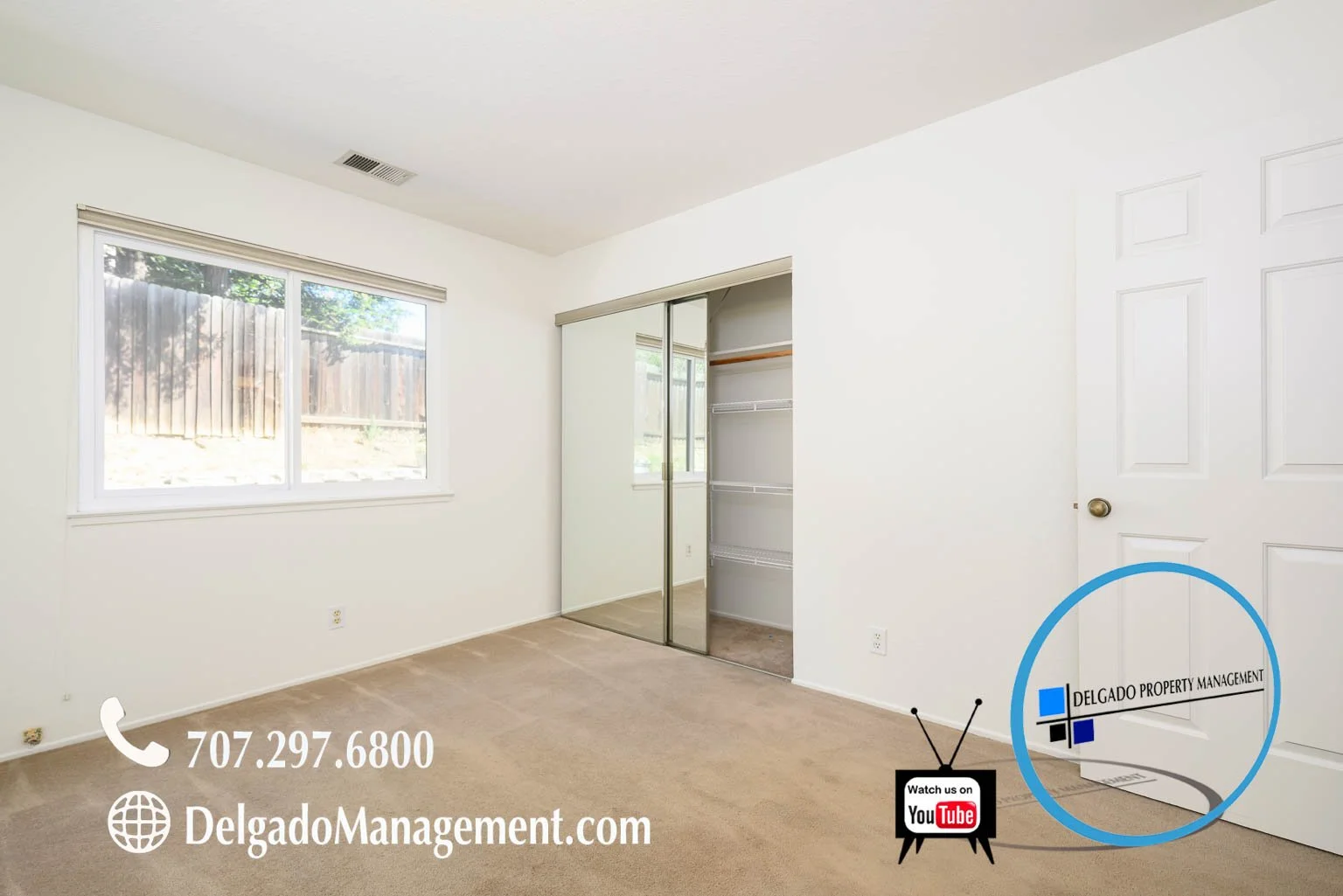 Empty bedroom with beige carpet, white walls, window with blinds, mirrored closet doors, and a white door. Contact information and branding for Delgado Property Management are overlaid on the image, along with a YouTube logo indicating to watch a vid