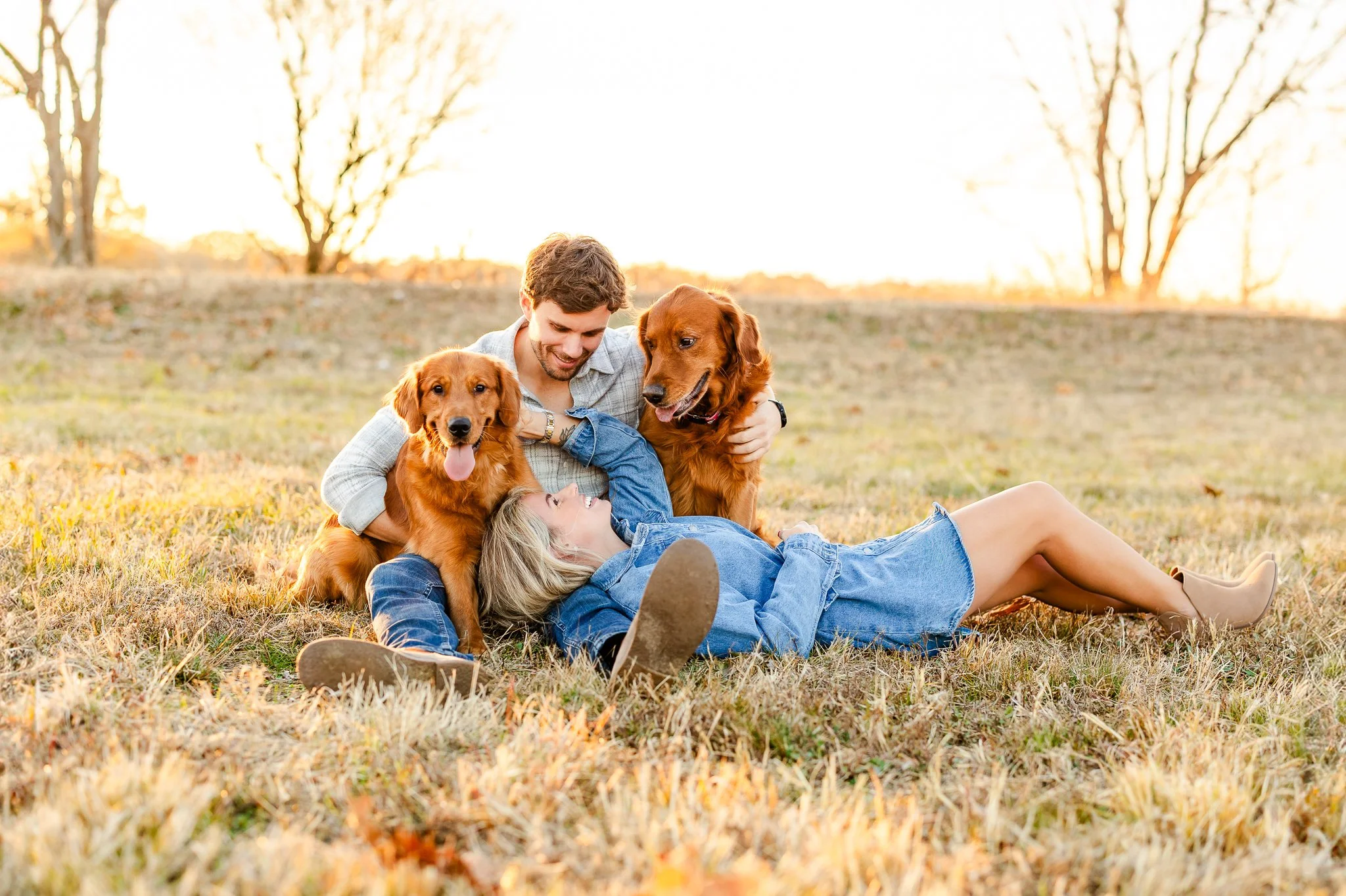 Couple with two golden retrievers lying on grass