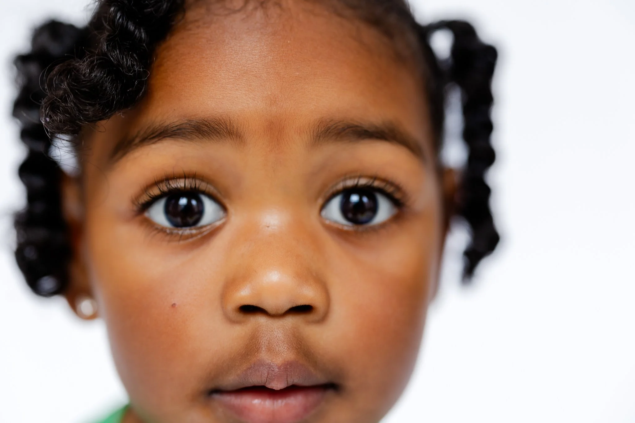 Close-up of a young child's face with large eyes and curly hair.