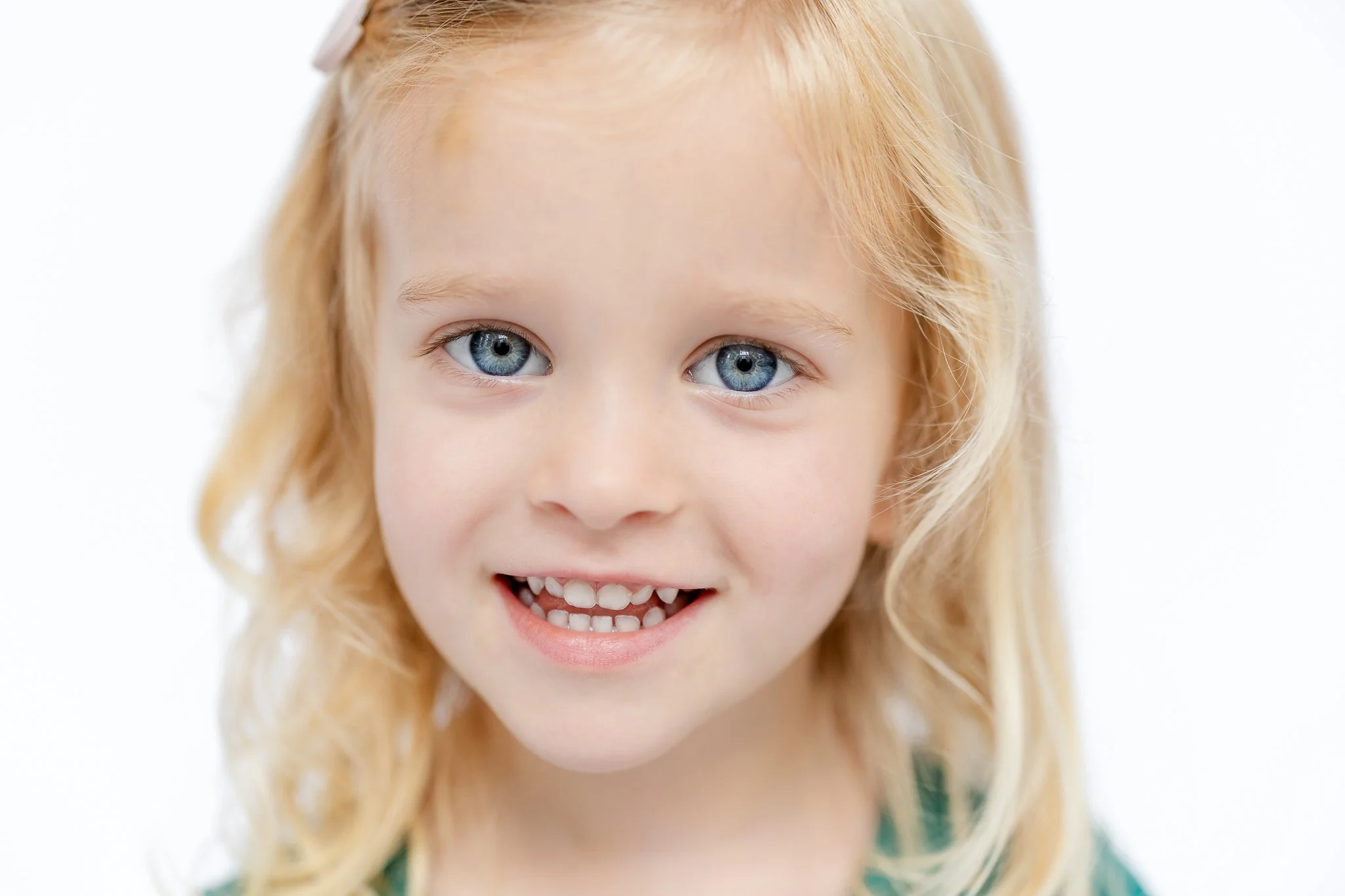 Smiling child with blonde hair and blue eyes.
