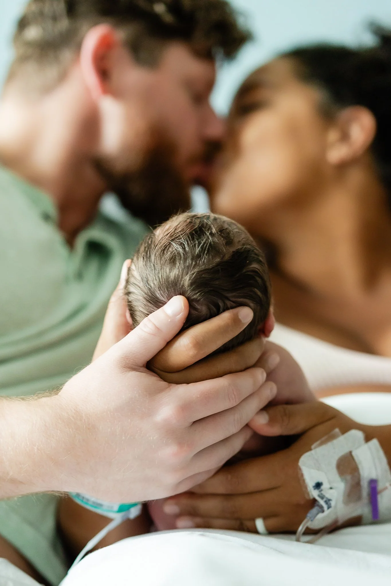 mom and dad holding baby close in the hospital room after birth in memphis 