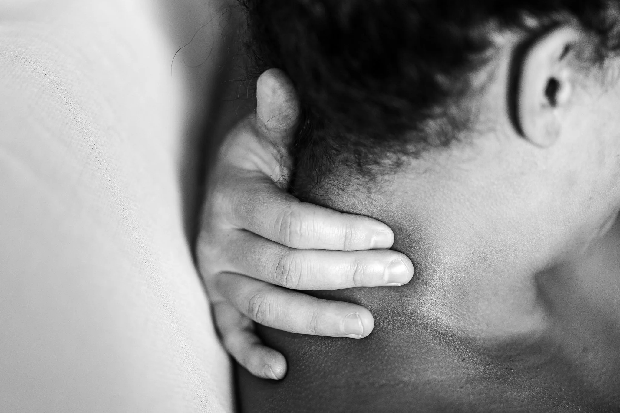 dad caressing the back of moms neck right after birth of their son 
