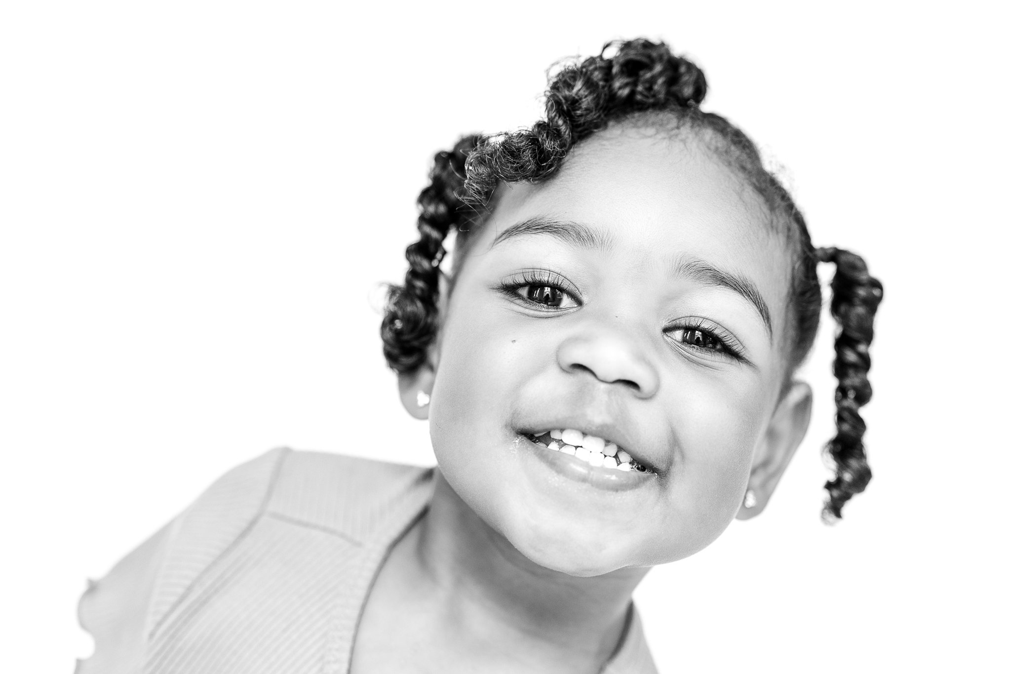 Smiling child with curly hair in black and white portrait.