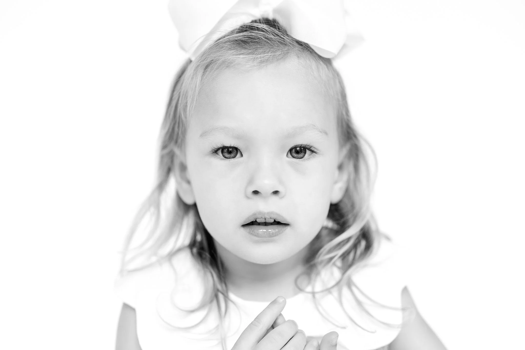 Black and white portrait of a young child with a white bow in their hair.
