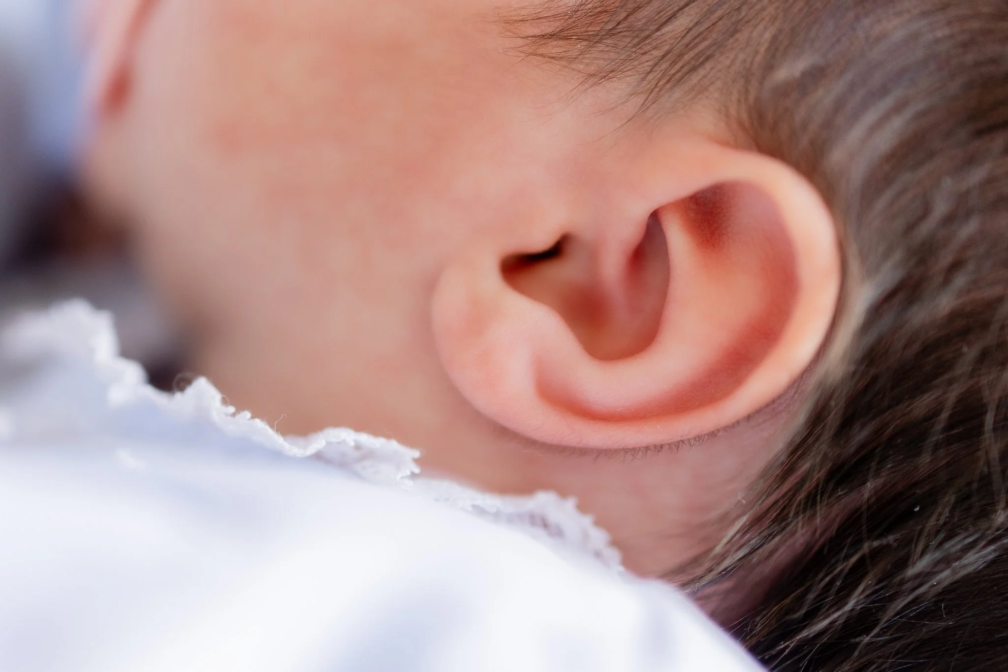 Close-up of a baby's ear and part of the head showing fine hair.