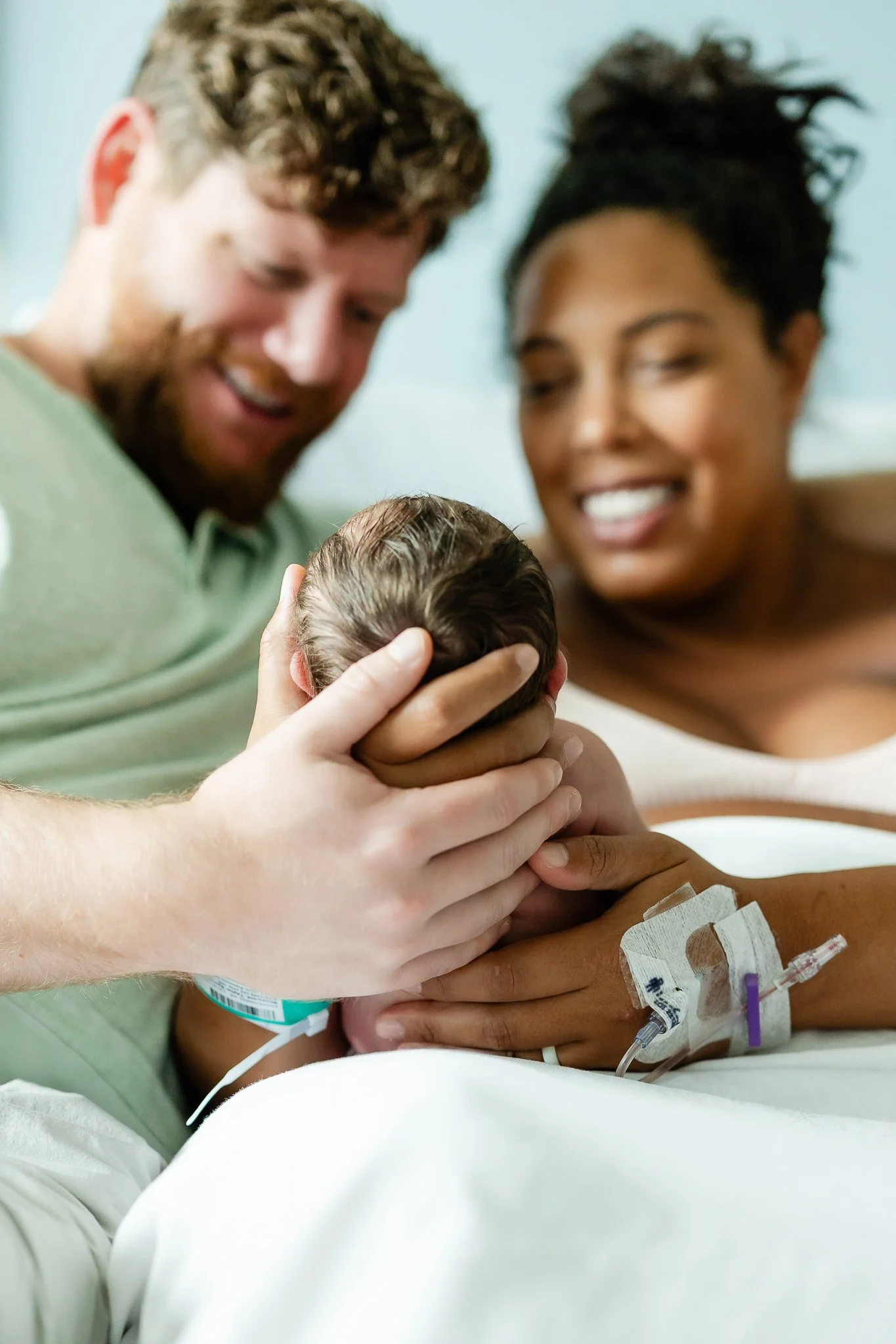 mom and dad hold baby day after birth in hospital room in memphis tn