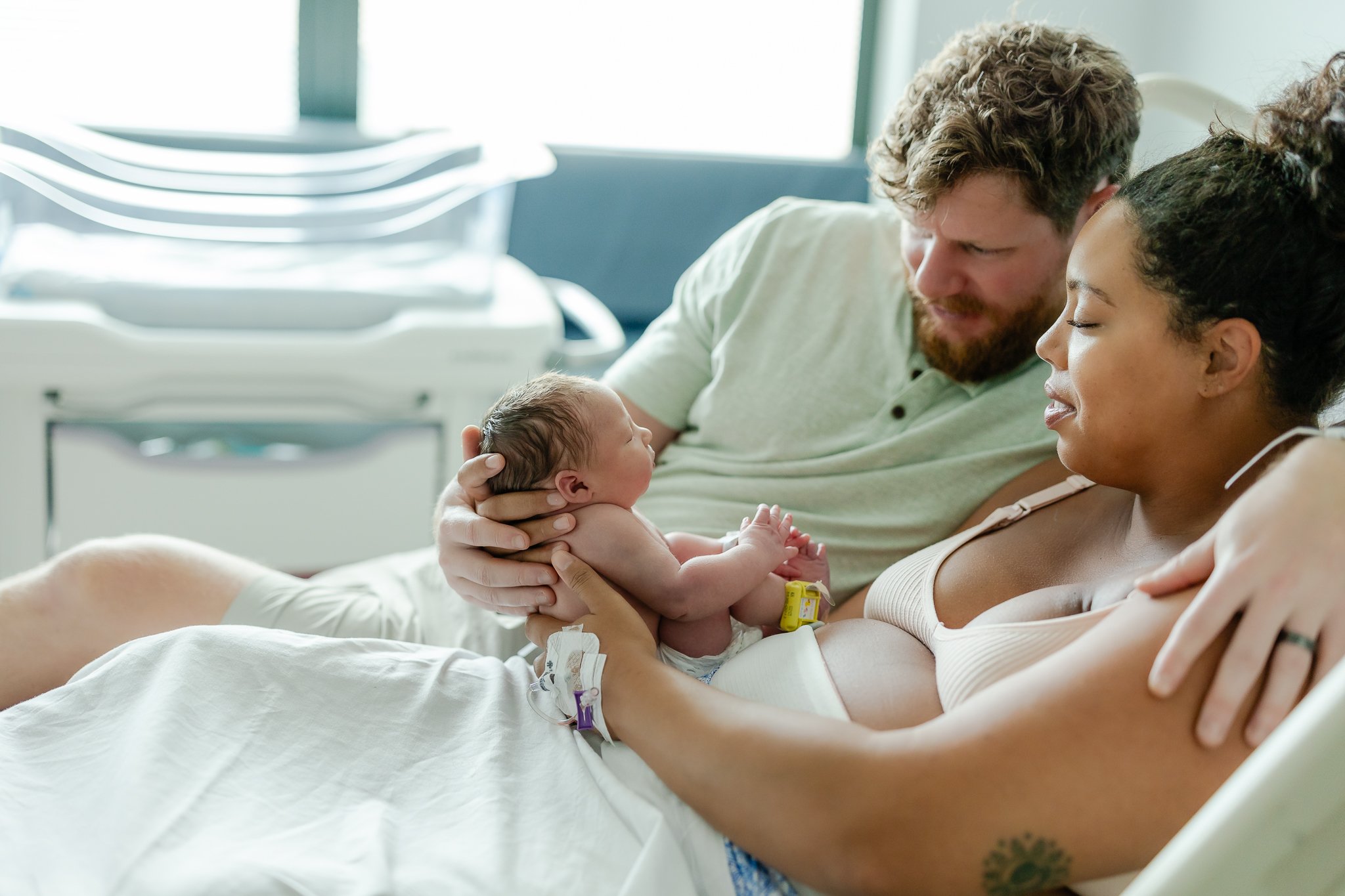 mom and dad holding baby close in the hospital room after birth in memphis 