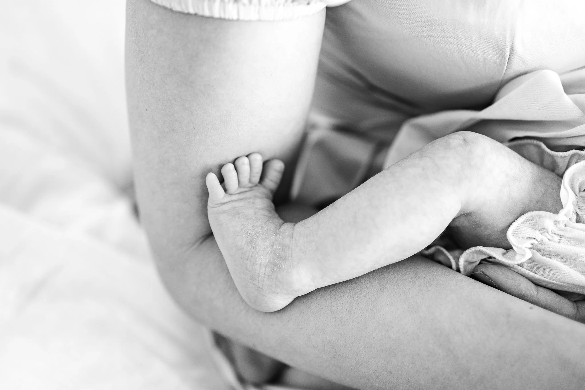 Black and white photo of a baby's foot on an adult's arm.