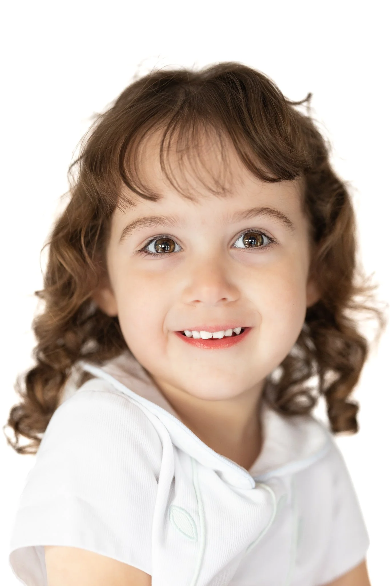 Smiling young child with curly hair in a white shirt in an heirloom portrait 