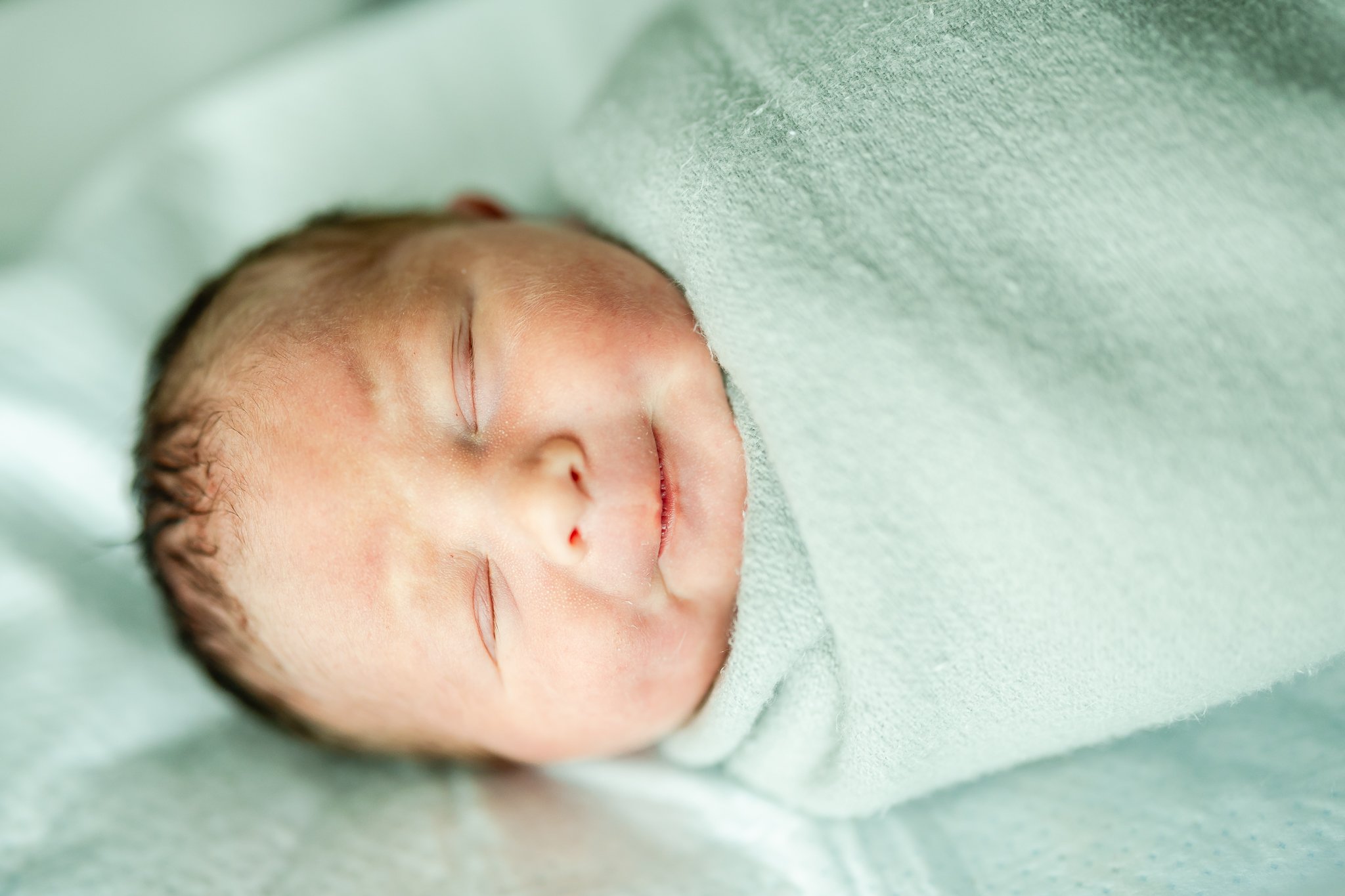 smiling newborn baby boy in the hospital after birth