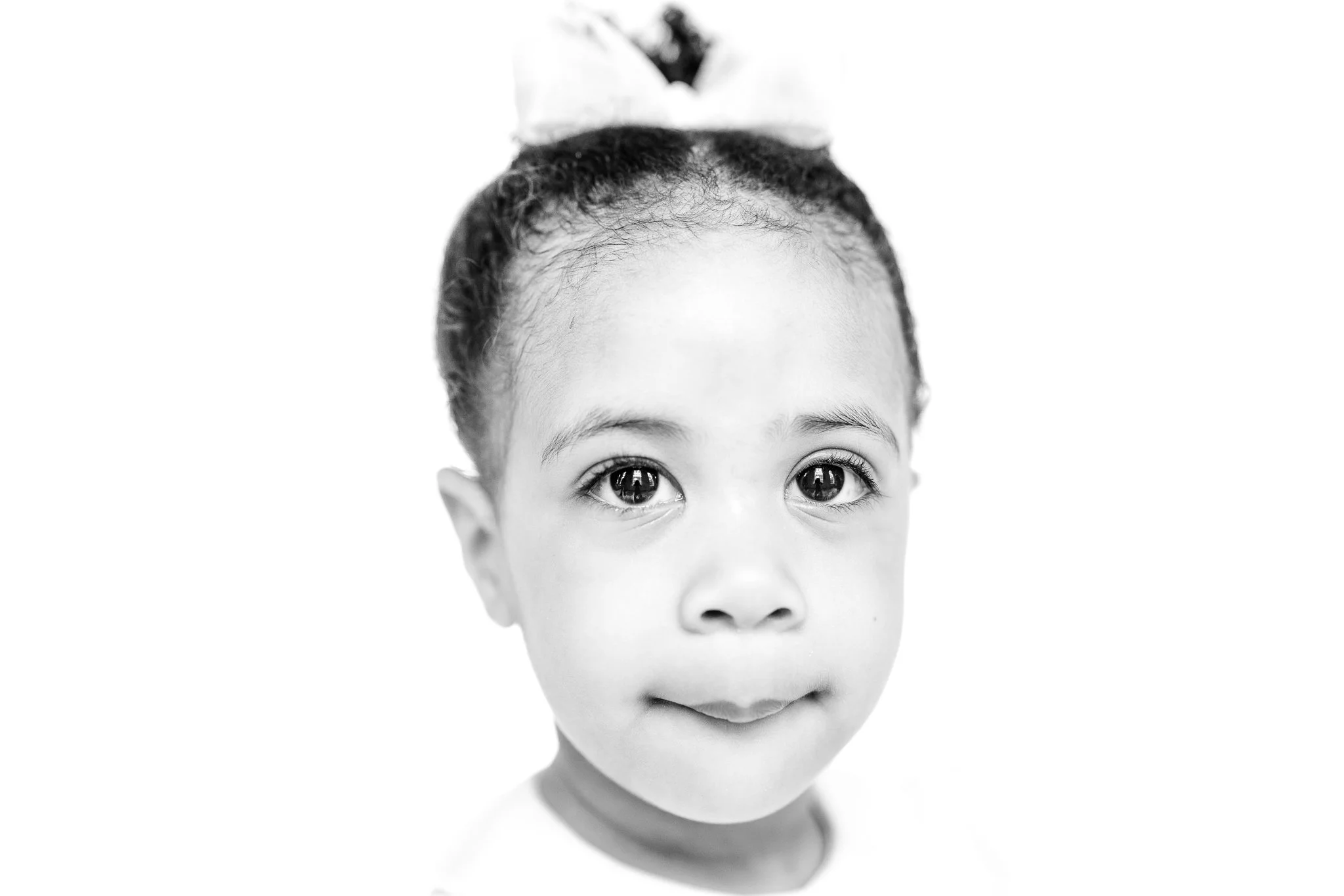 Black and white portrait of a young child with a bow in her hair