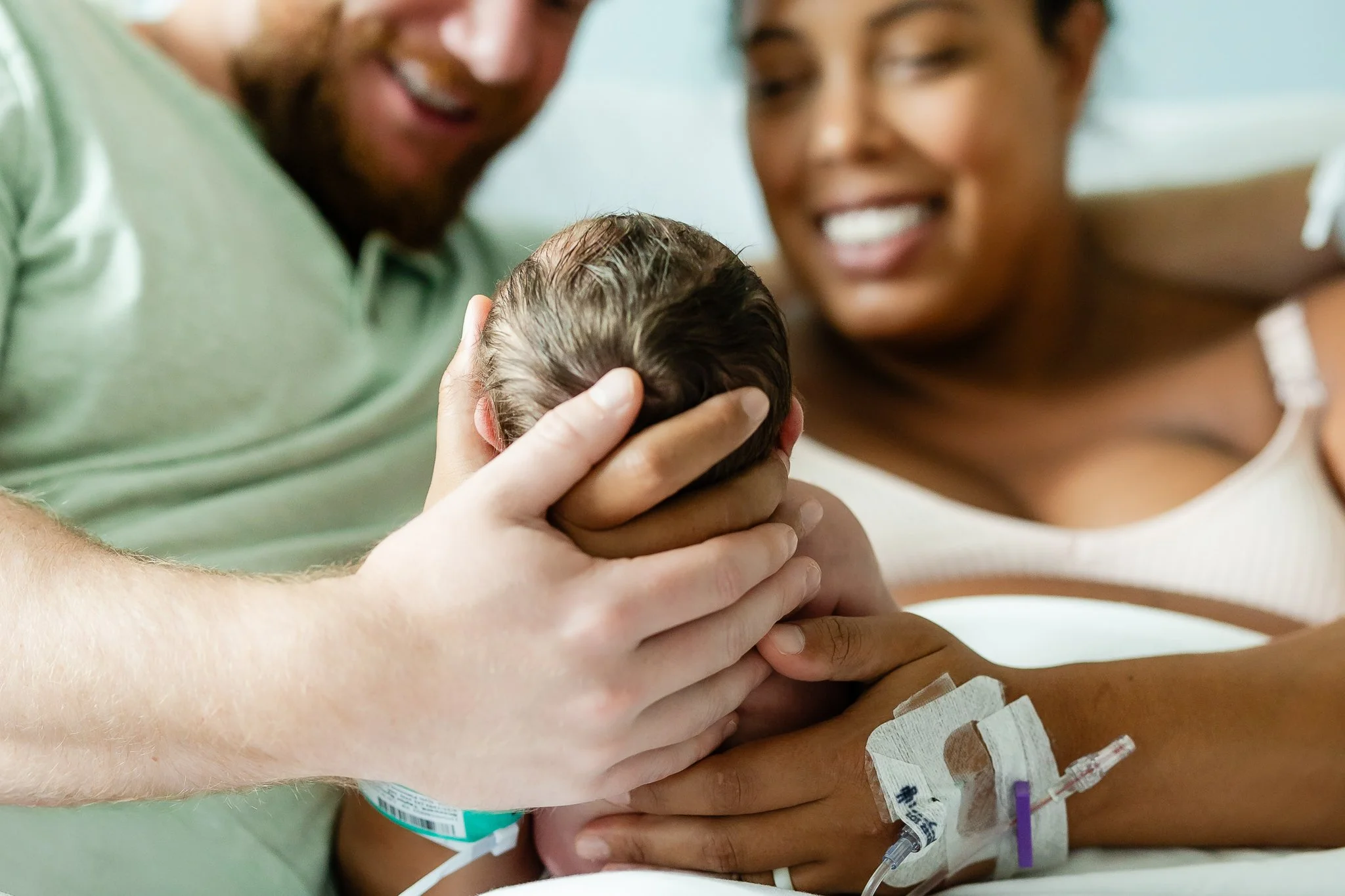 mom and dad holding baby close in the hospital room after birth in memphis 