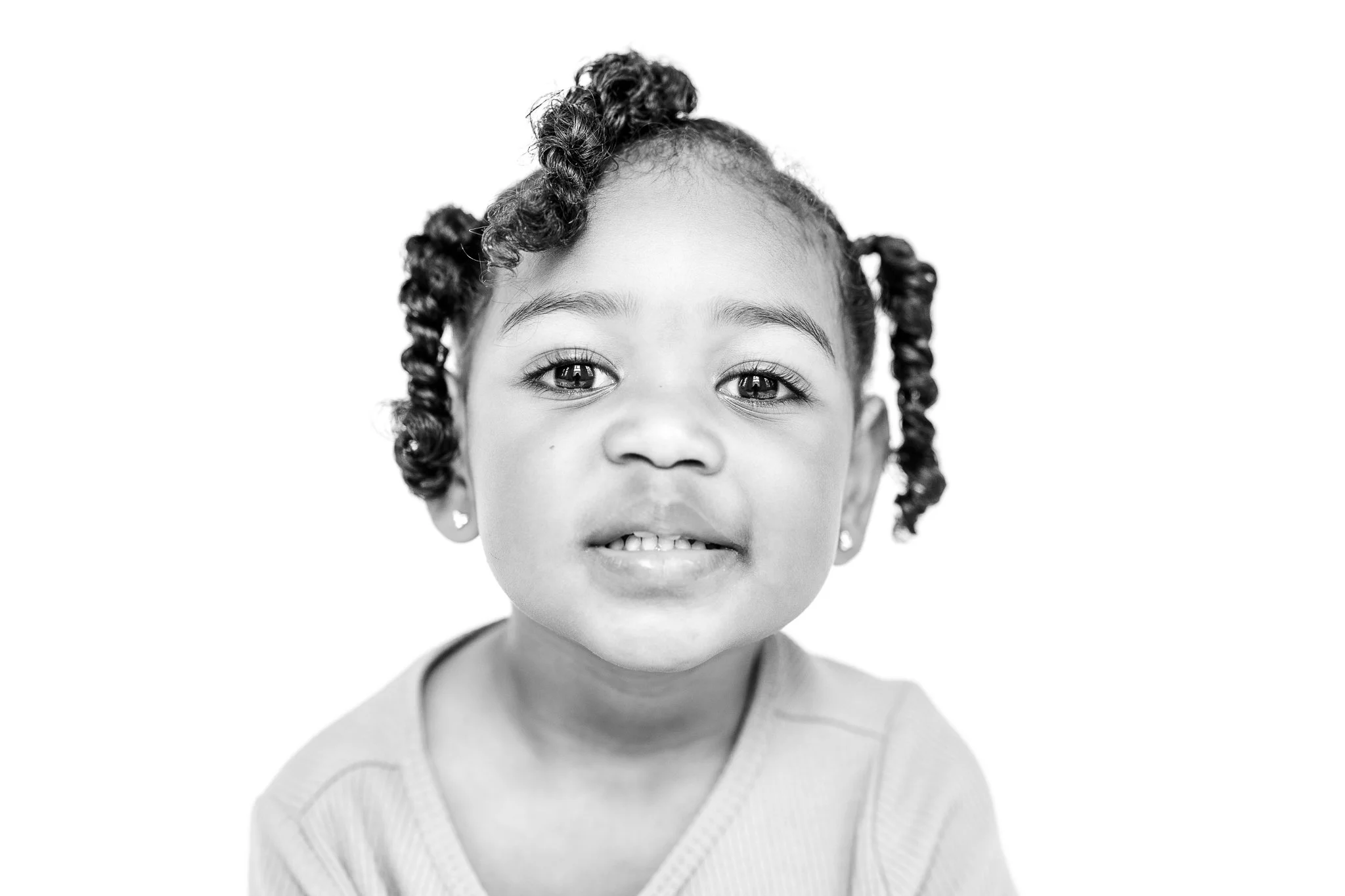 Close-up black and white photo of a young child with curly hair.
