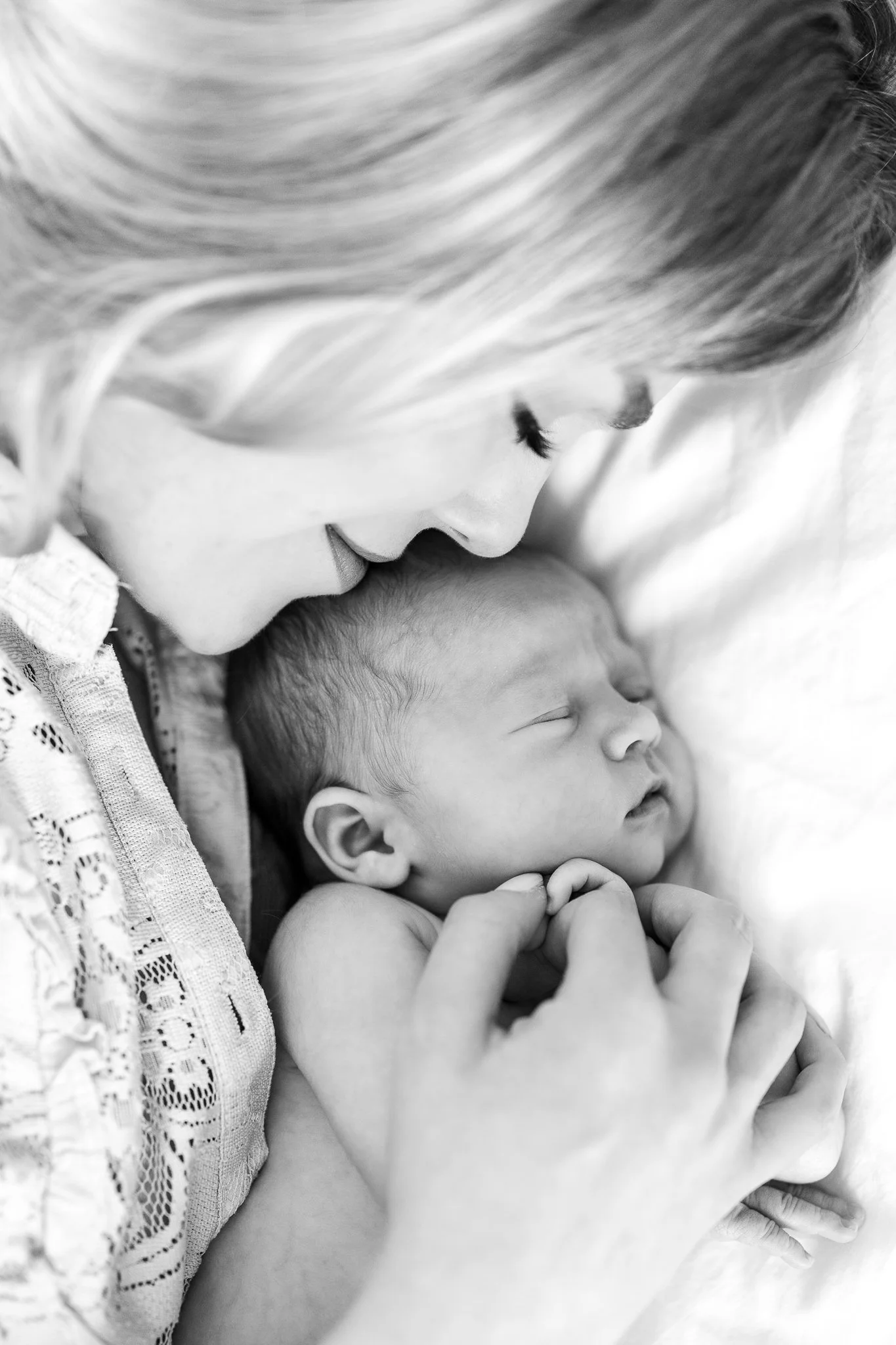 Black and white photo of a woman lovingly holding a sleeping newborn baby.