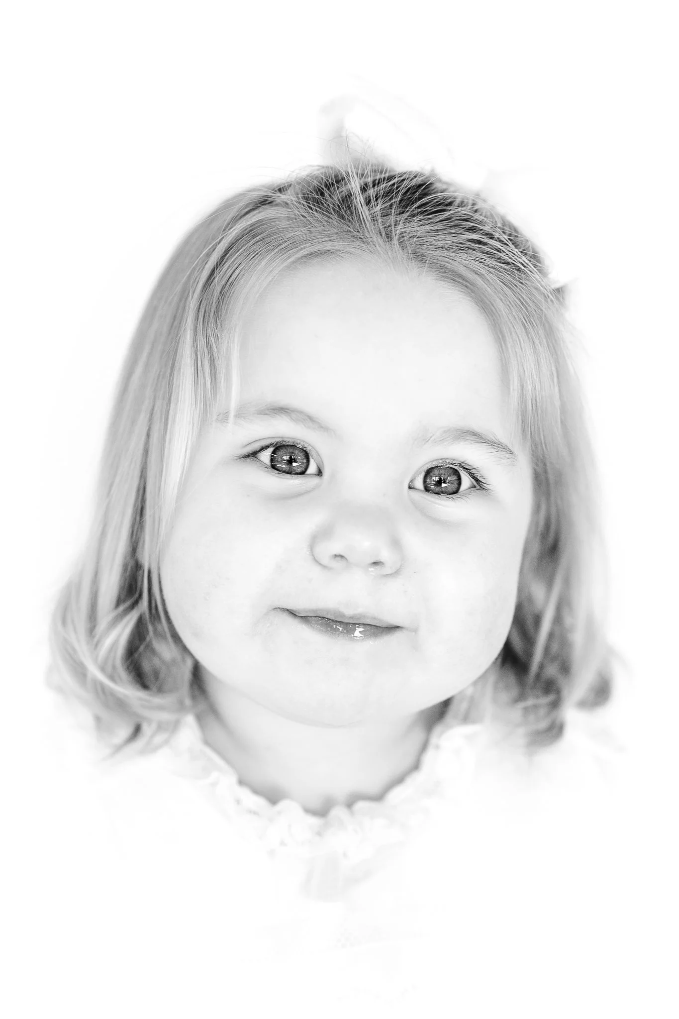 Black and white portrait of a young child with light hair, smiling slightly.
