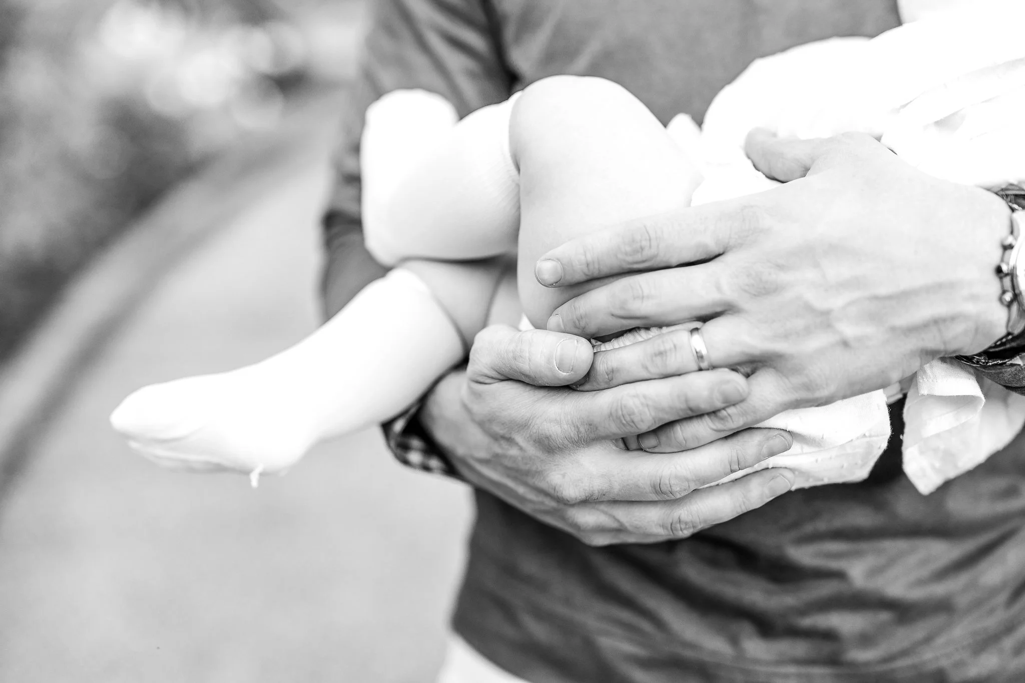 Close-up of an adult holding a small child wrapped in a blanket, emphasizing the hands and arms.