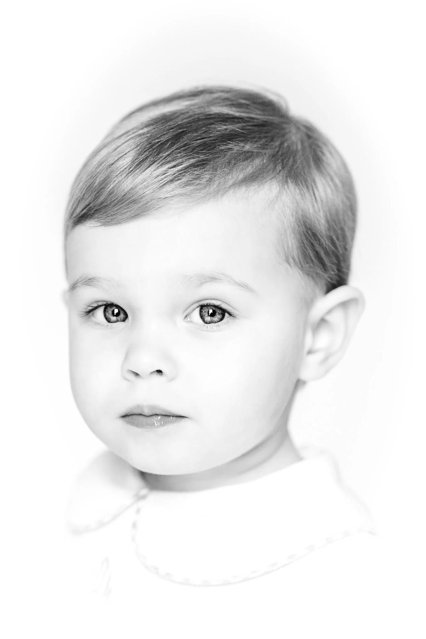 Black and white portrait of a young child with light hair, wearing a collared shirt.