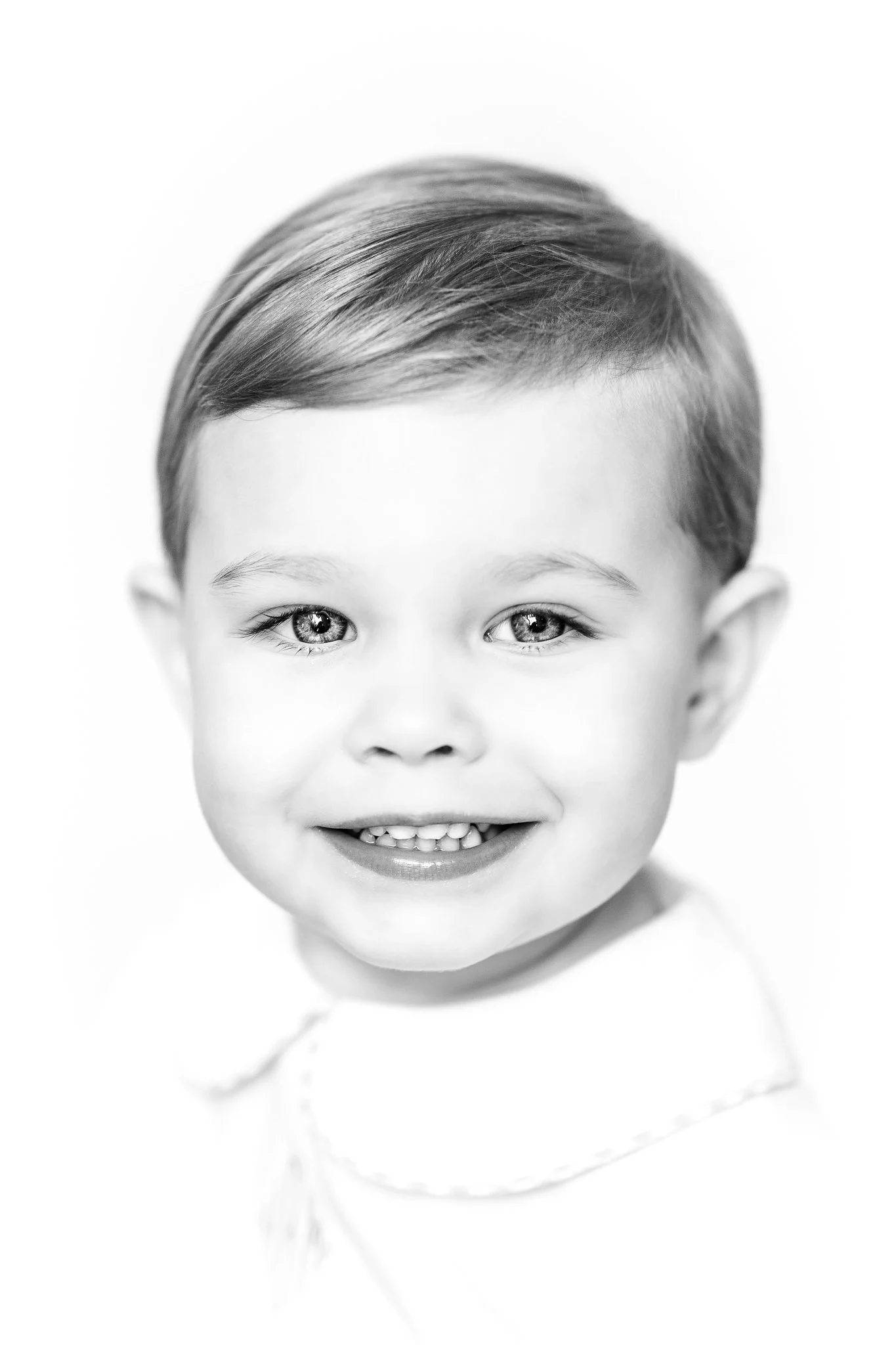 Black and white portrait of a smiling child with short hair.