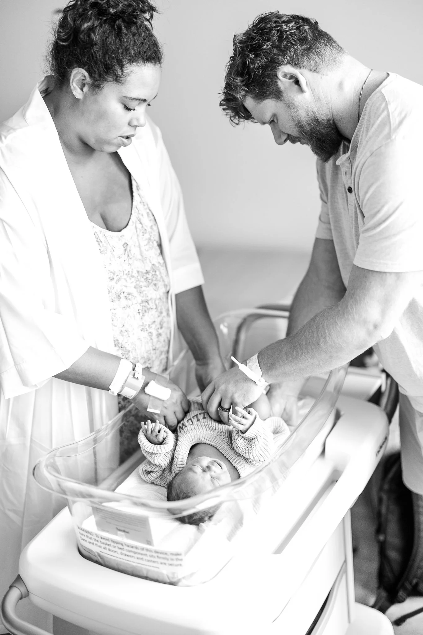 new parents working together to change their newborn sons clothes in the hospital after birth