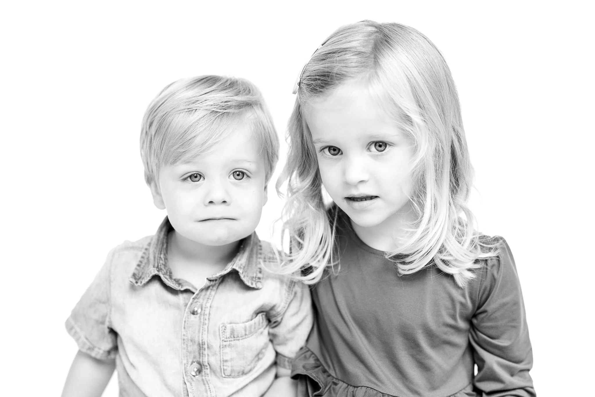 Black and white portrait of a young boy and girl, each with light hair, facing forward.