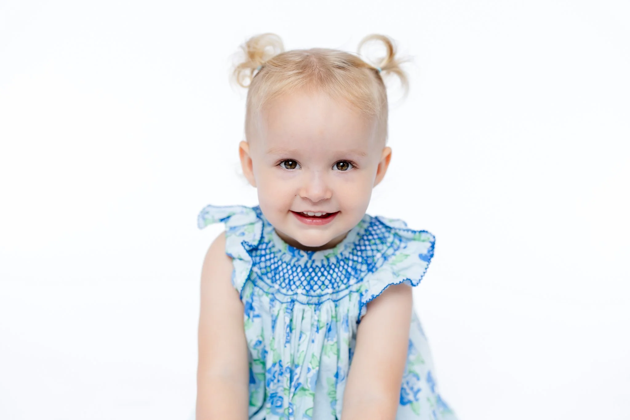 Smiling toddler with pigtails wearing floral dress