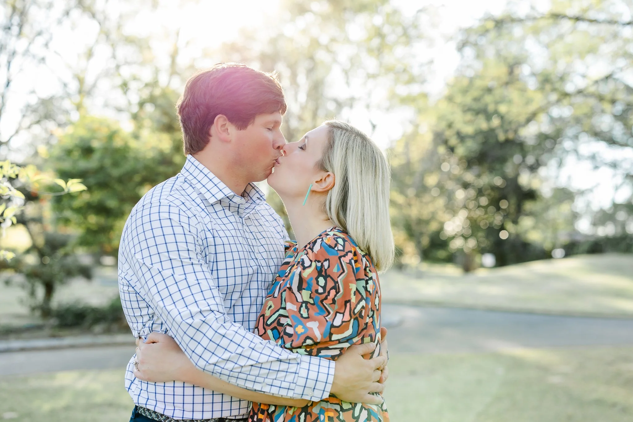 Couple kissing outdoors in a park setting.