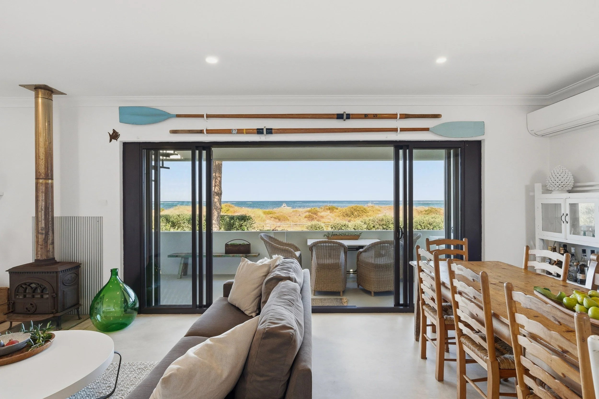 Living and dining area opening onto a balcony with coastal views.