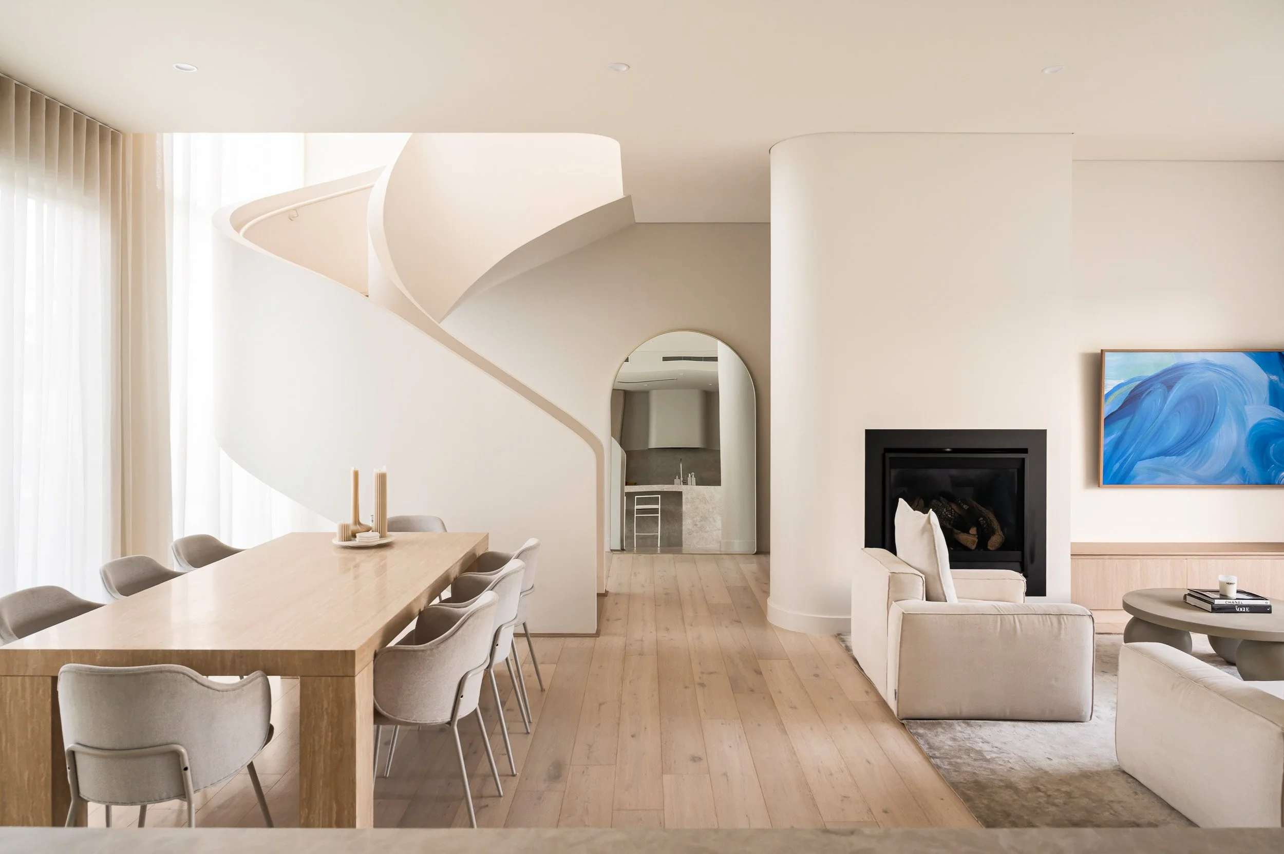 Bright open-plan dining and living area with arched openings and a dark fireplace.