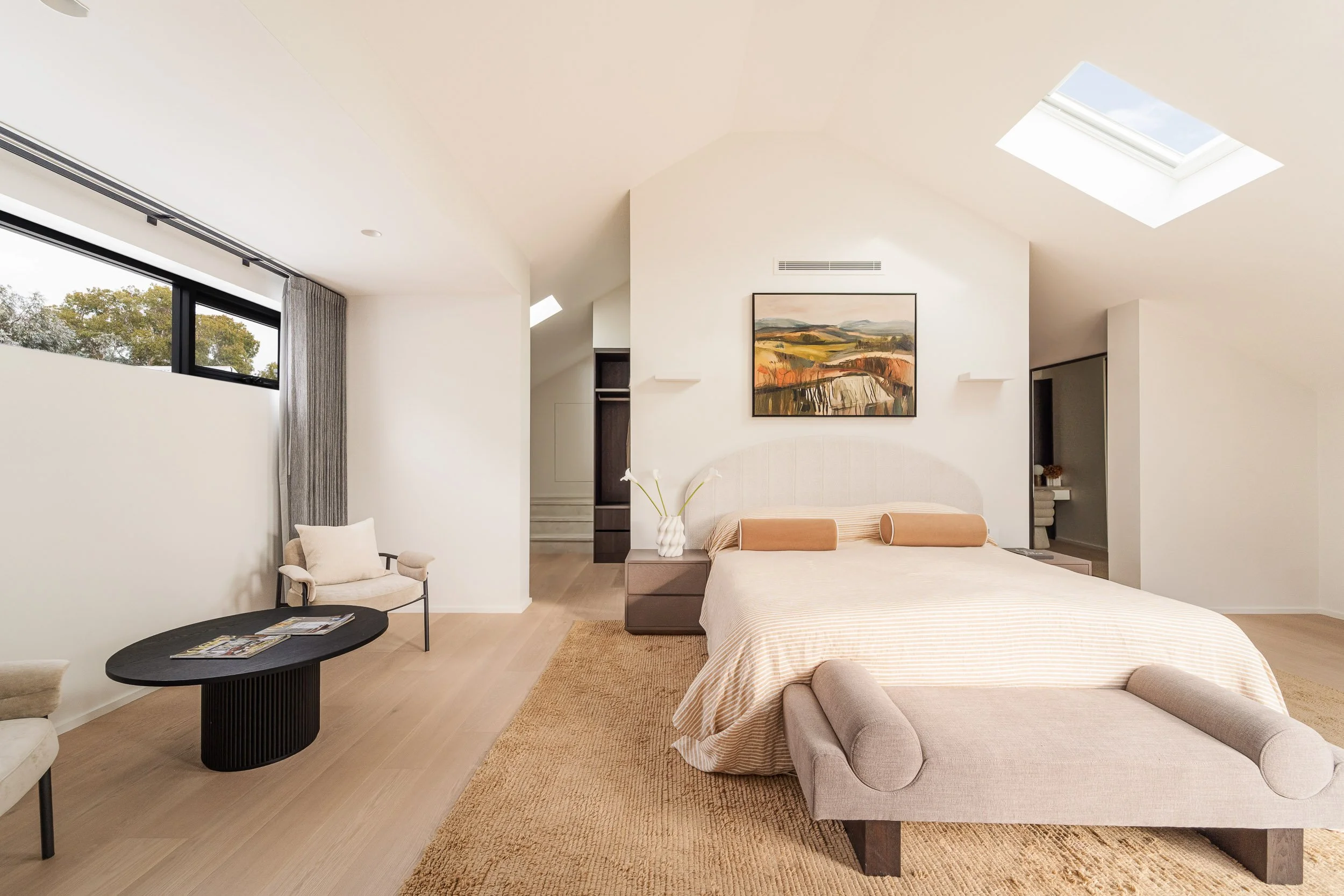 Bedroom with soft white bedding, neutral finishes and a recessed wall display.