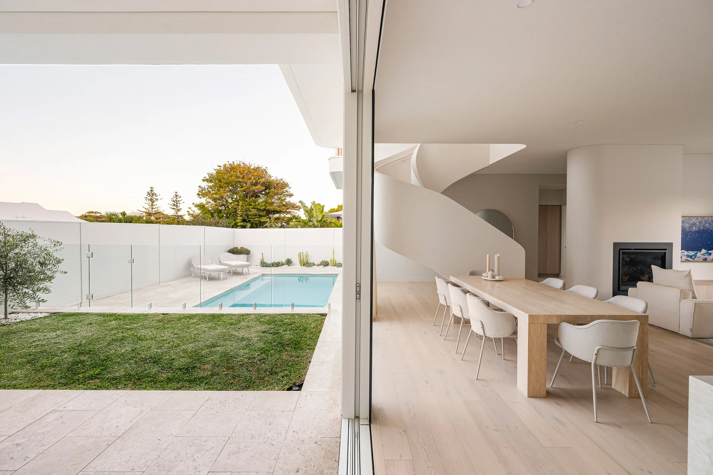 Kitchen opening onto a sheltered courtyard with a small lawn and planted boundary wall.