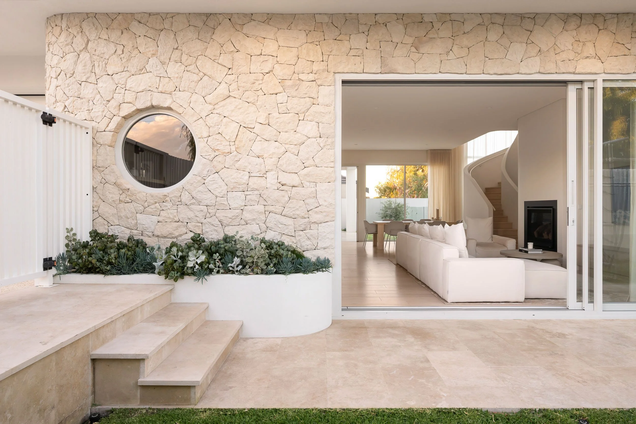 Stone-walled courtyard with a circular window and a wide opening to the living room.
