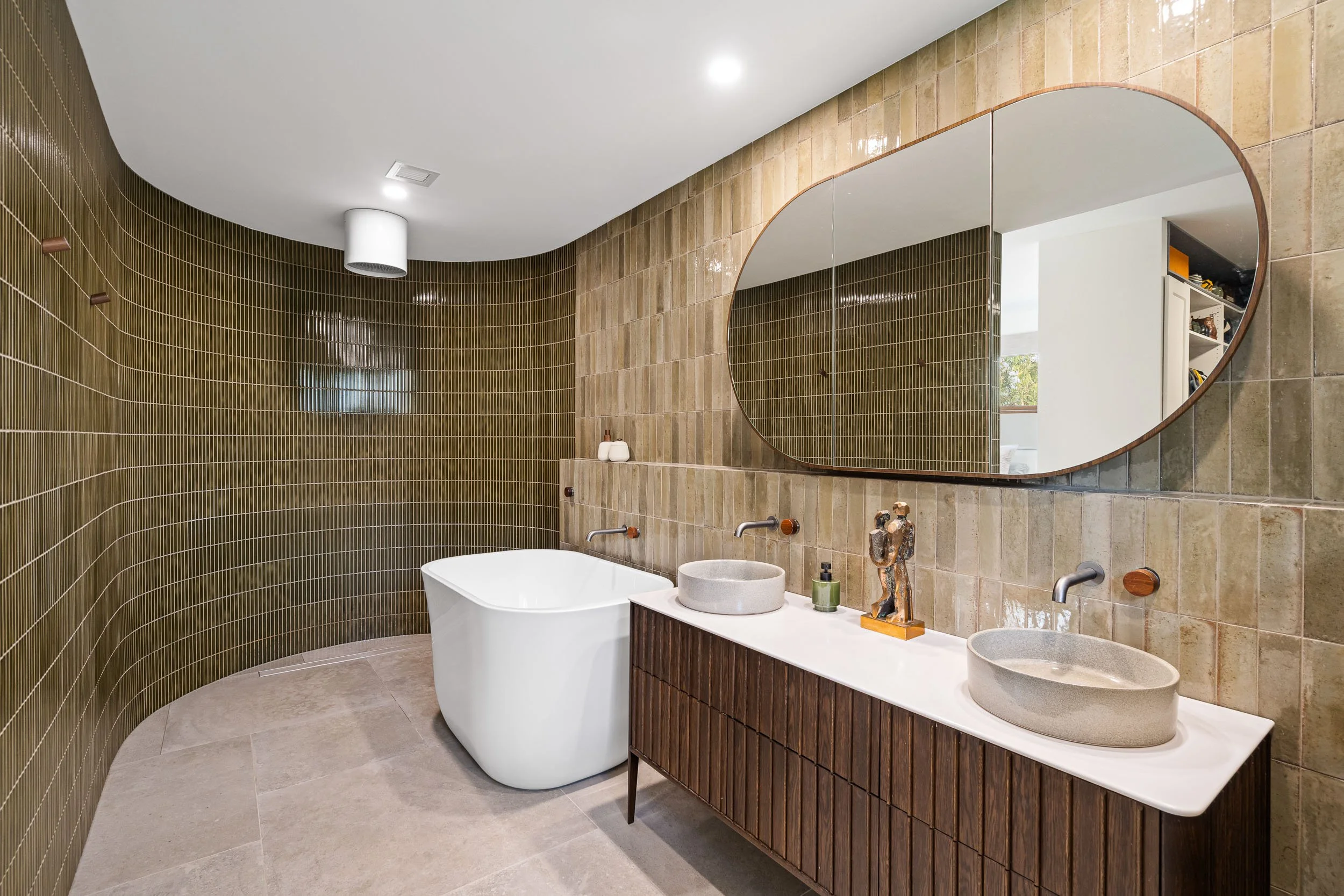 Bathroom with a freestanding bath, long double vanity and warm timber-toned finishes.