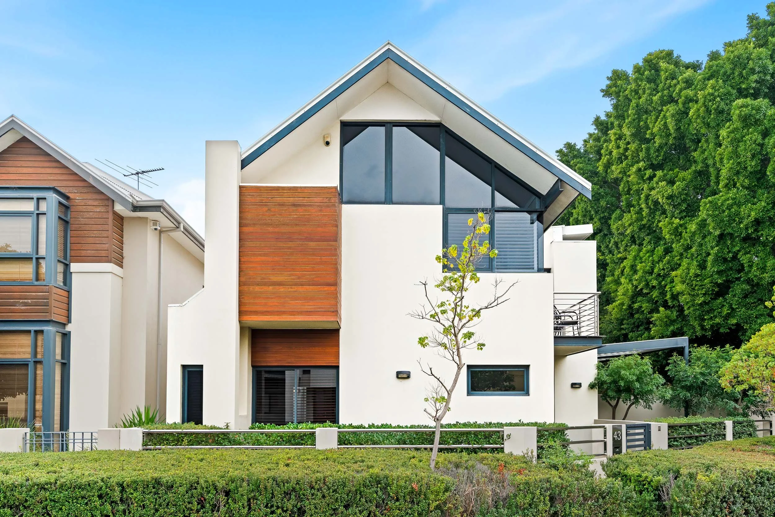 Contemporary two-storey home with a gabled roof, white walls and contrasting timber-look cladding.