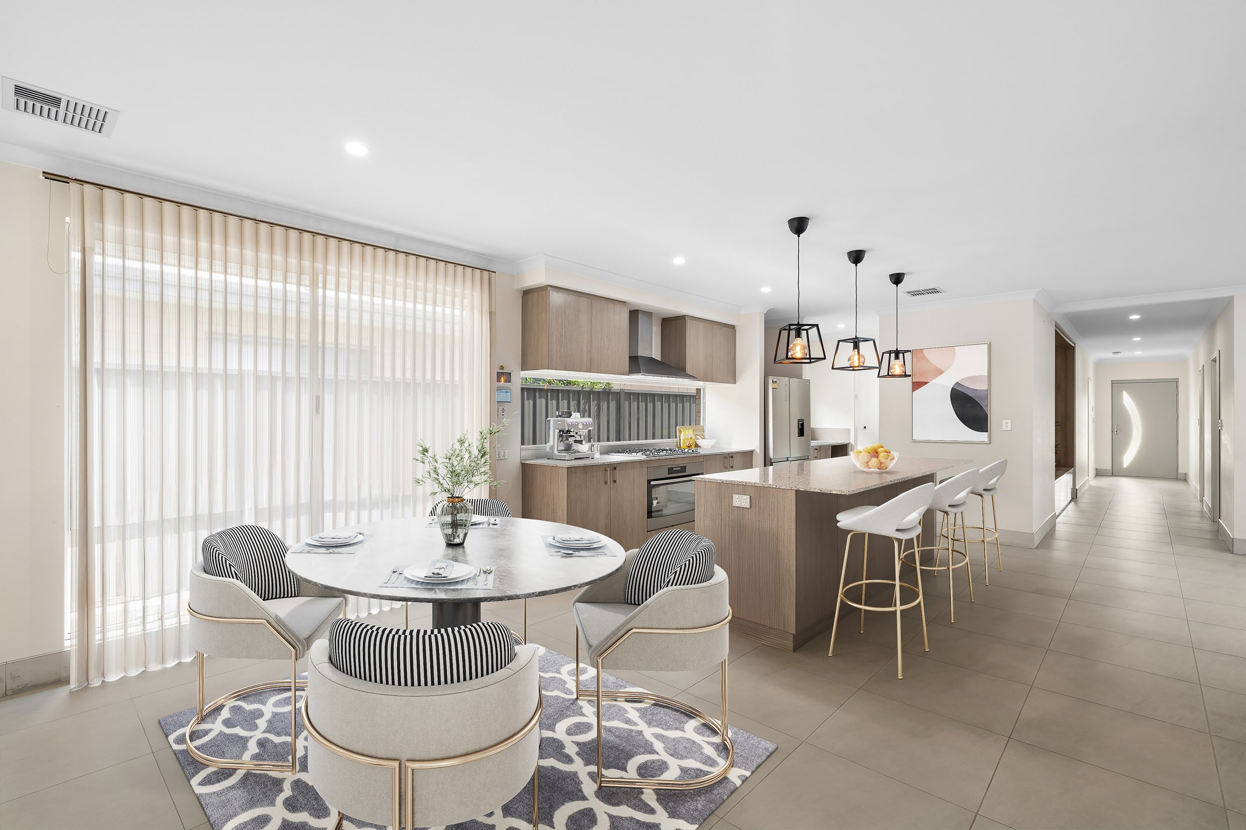 Virtually staged dining area with a round table, upholstered chairs and an adjoining modern kitchen.