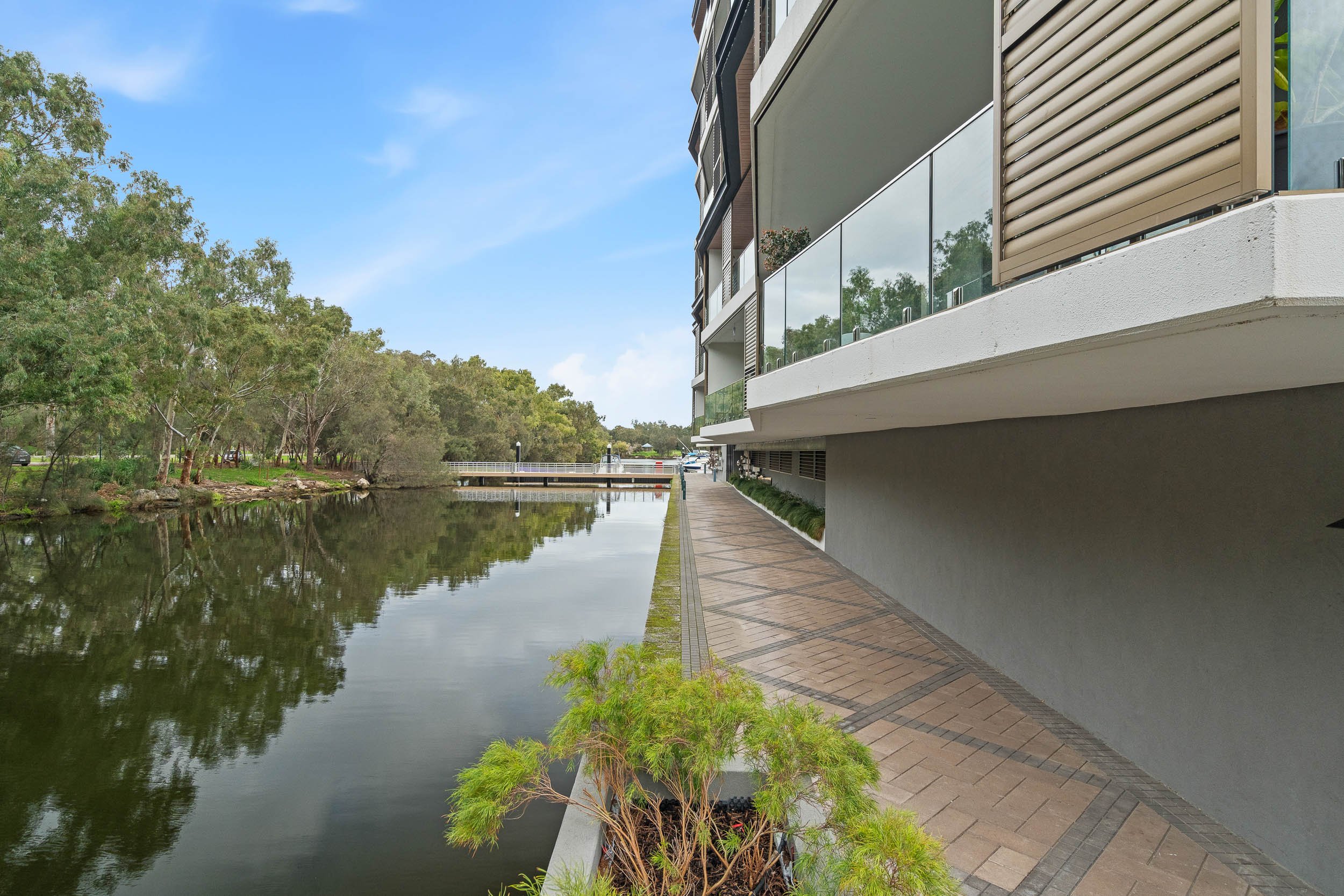 Waterfront apartment building beside a calm canal, with reflections on the water.