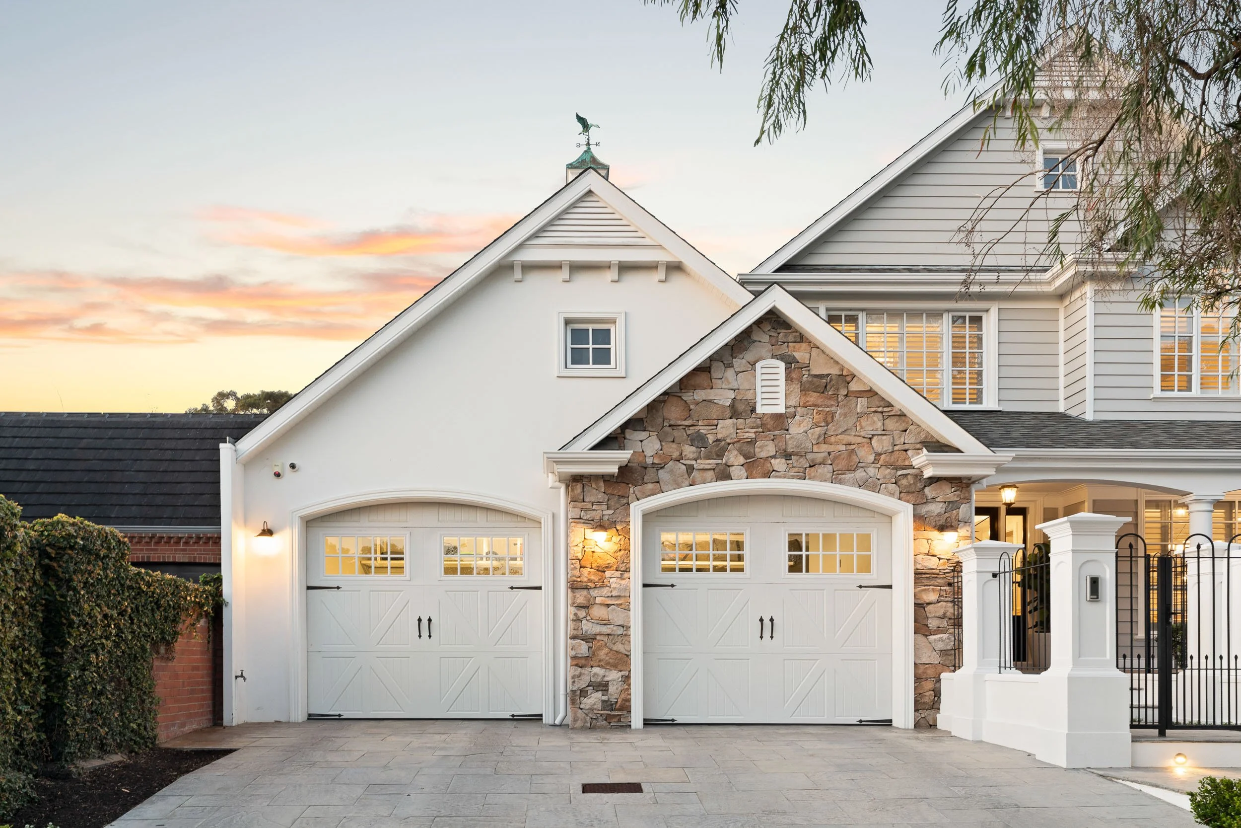 Double garage with arched white doors, stone-clad gables and decorative roof details.