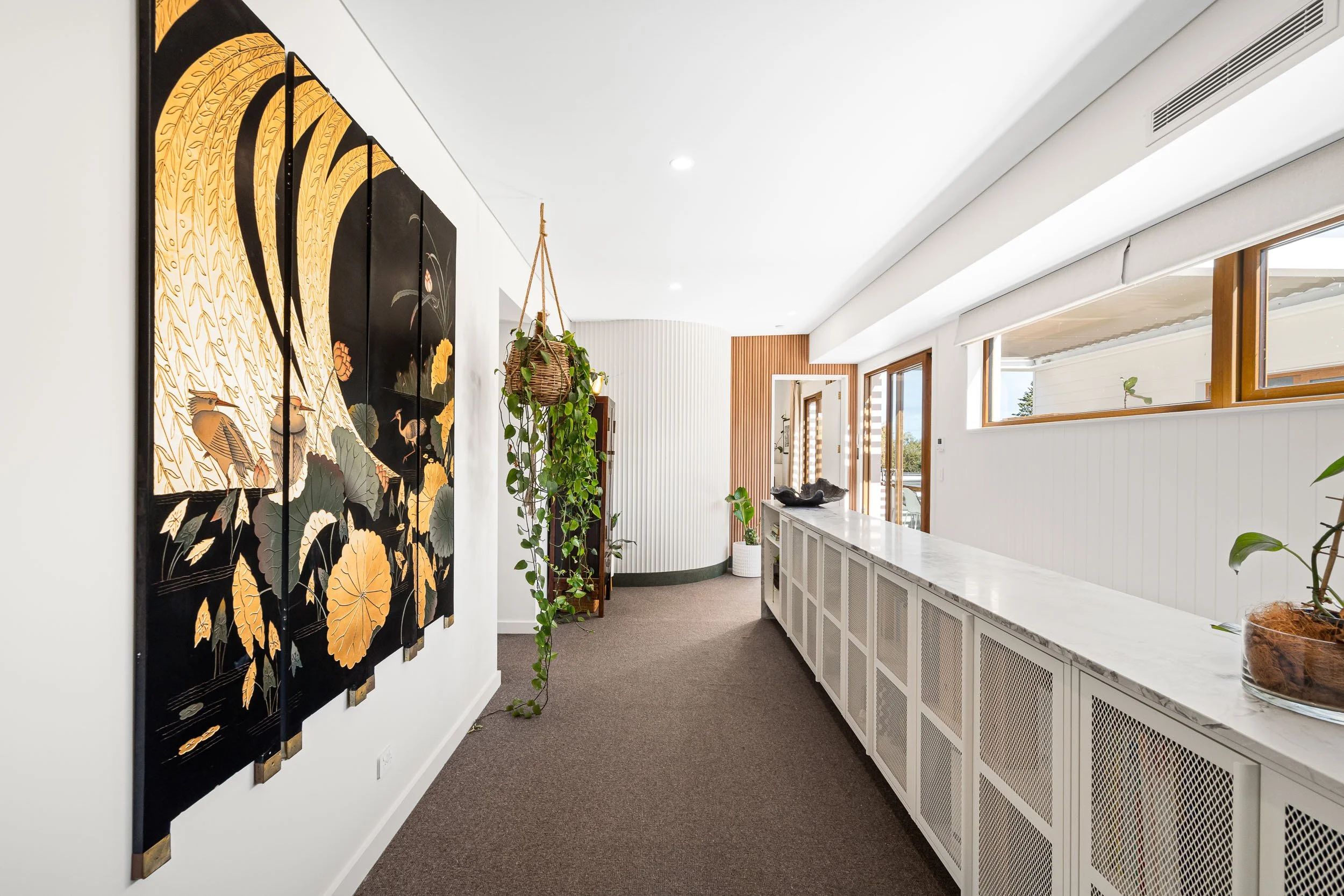 Hallway with a long built-in console, contemporary artwork and high windows.