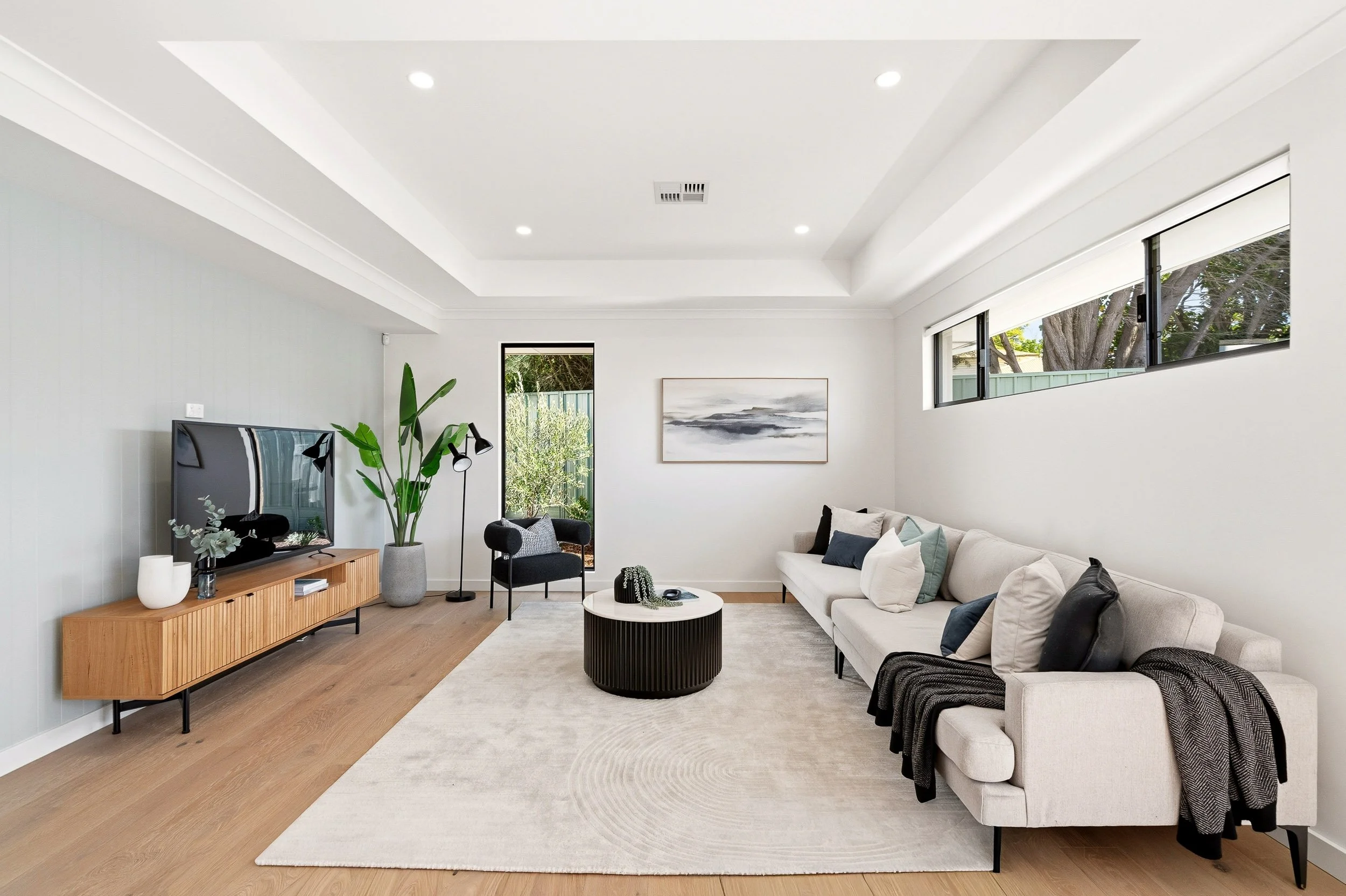 Living room with grey sofas, timber flooring and a recessed feature ceiling.
