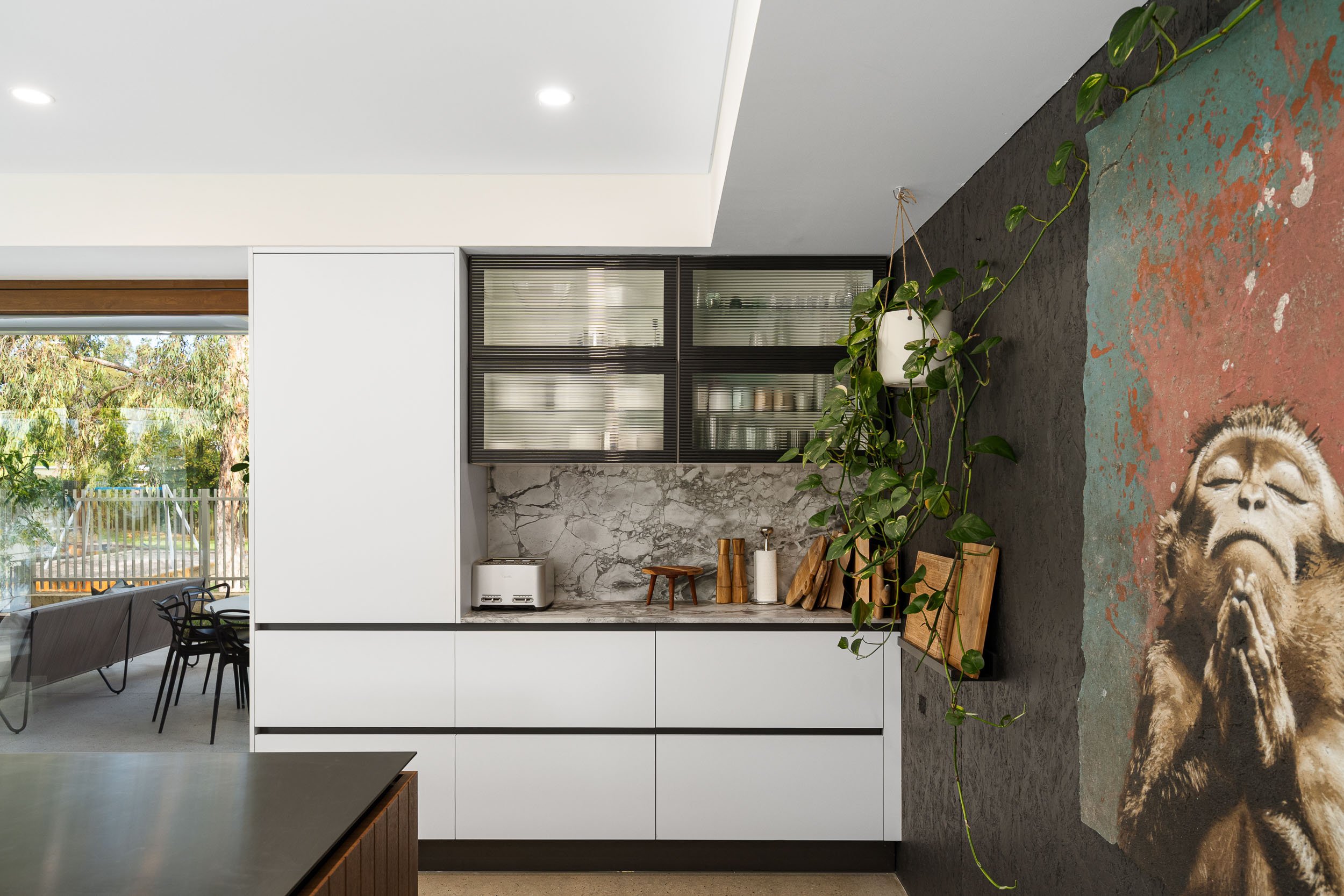Kitchen cabinetry with a glazed display cupboard, white drawers and a stone splashback.