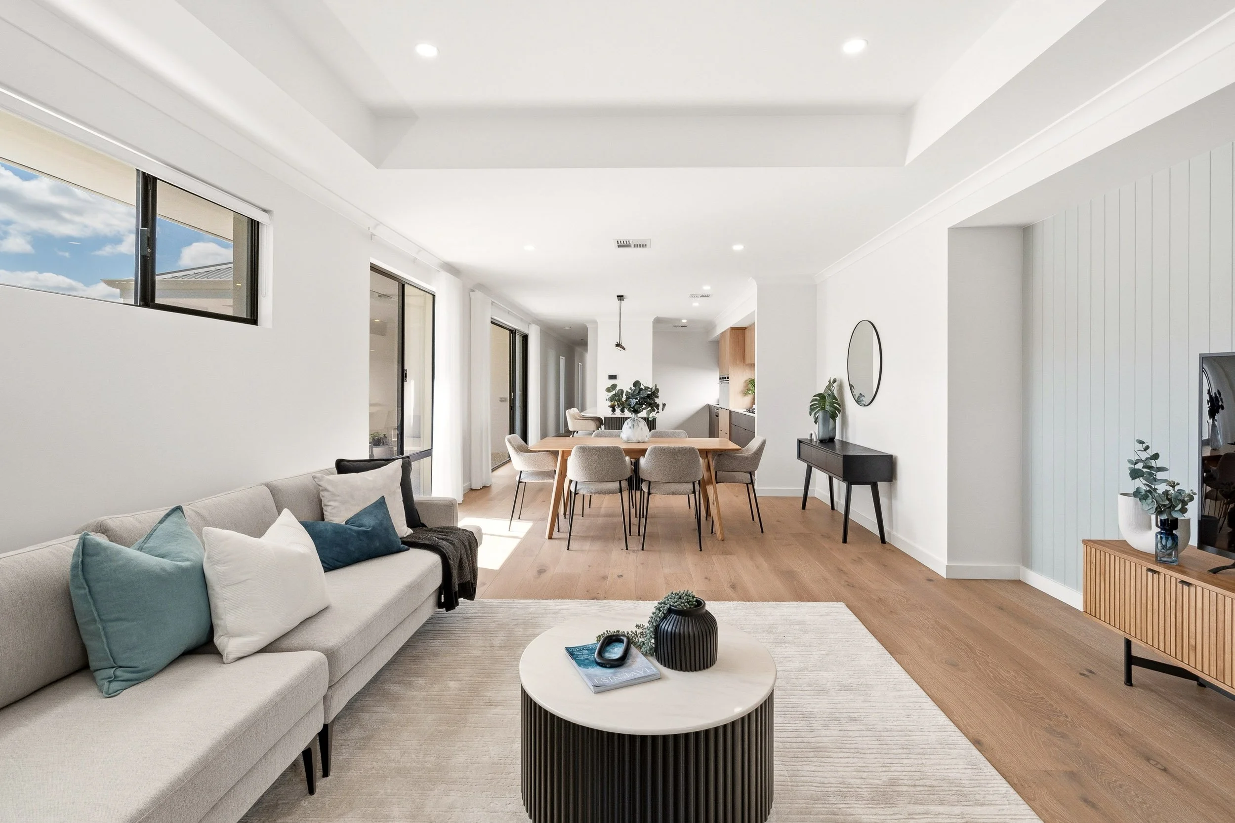 Open-plan living and dining room with timber floors and a white coffered ceiling.