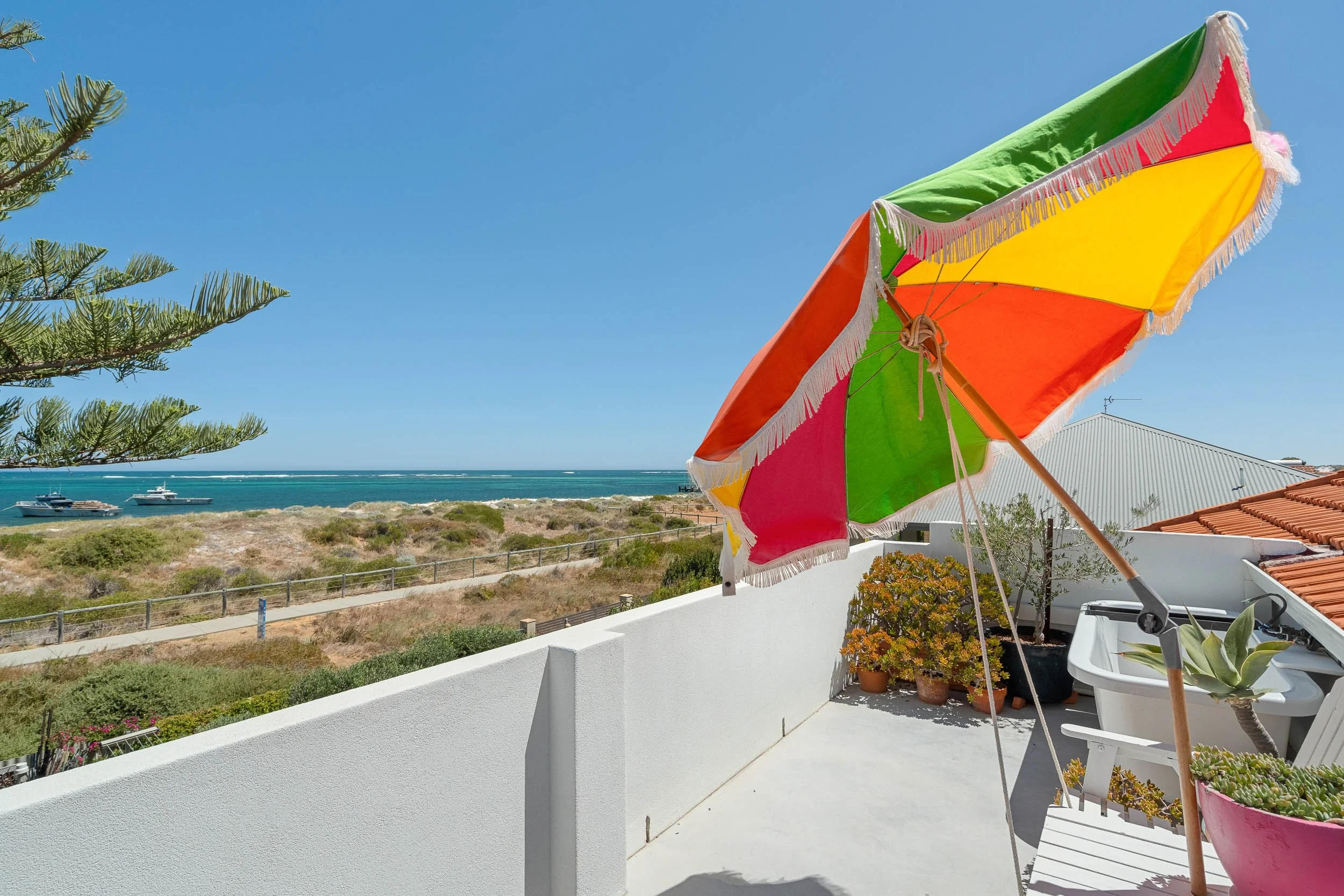 Coastal balcony with a rainbow flag and views of the ocean and nearby boats.