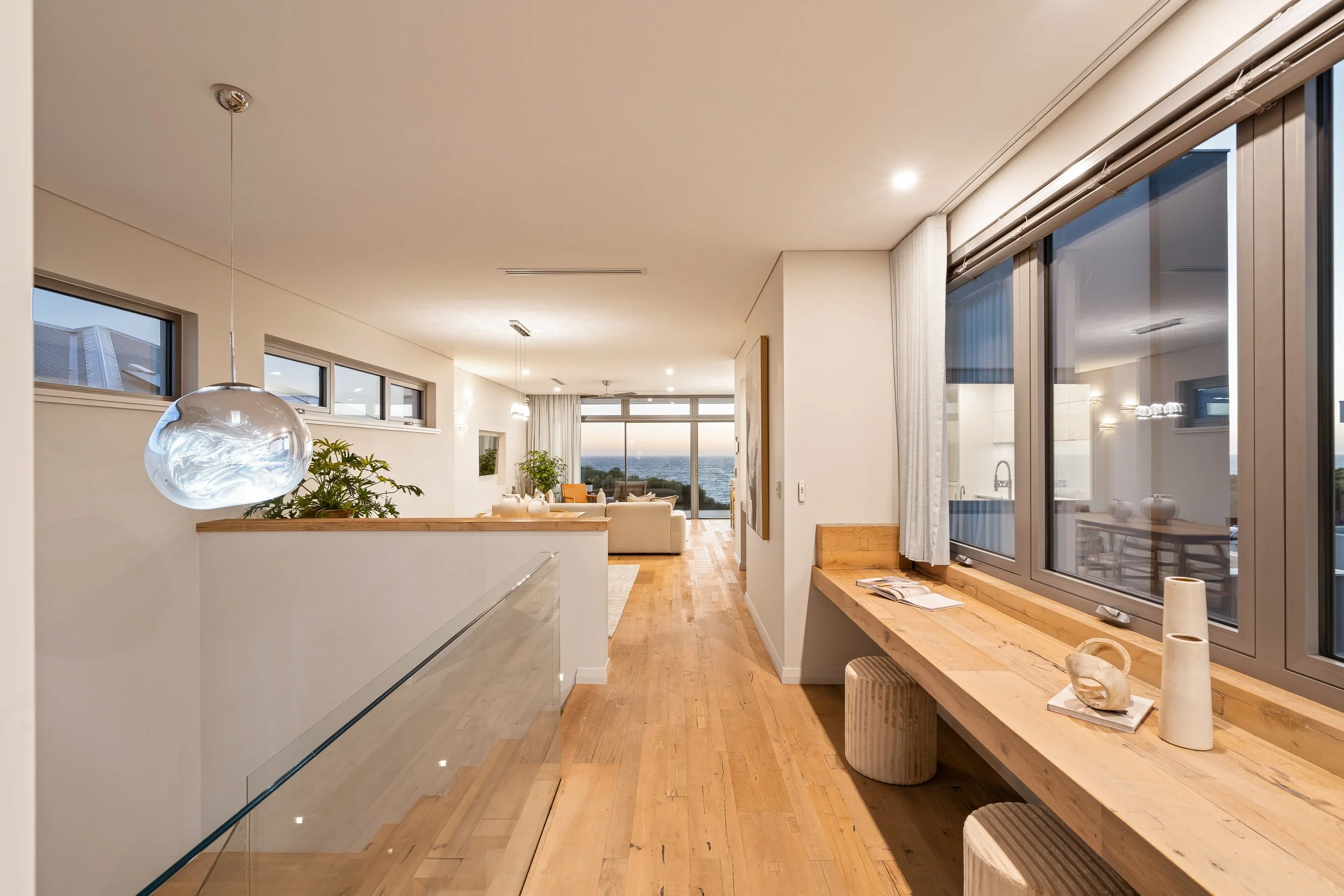 Upper landing with a timber window bench, glass pendant lights and a view across the stairwell.