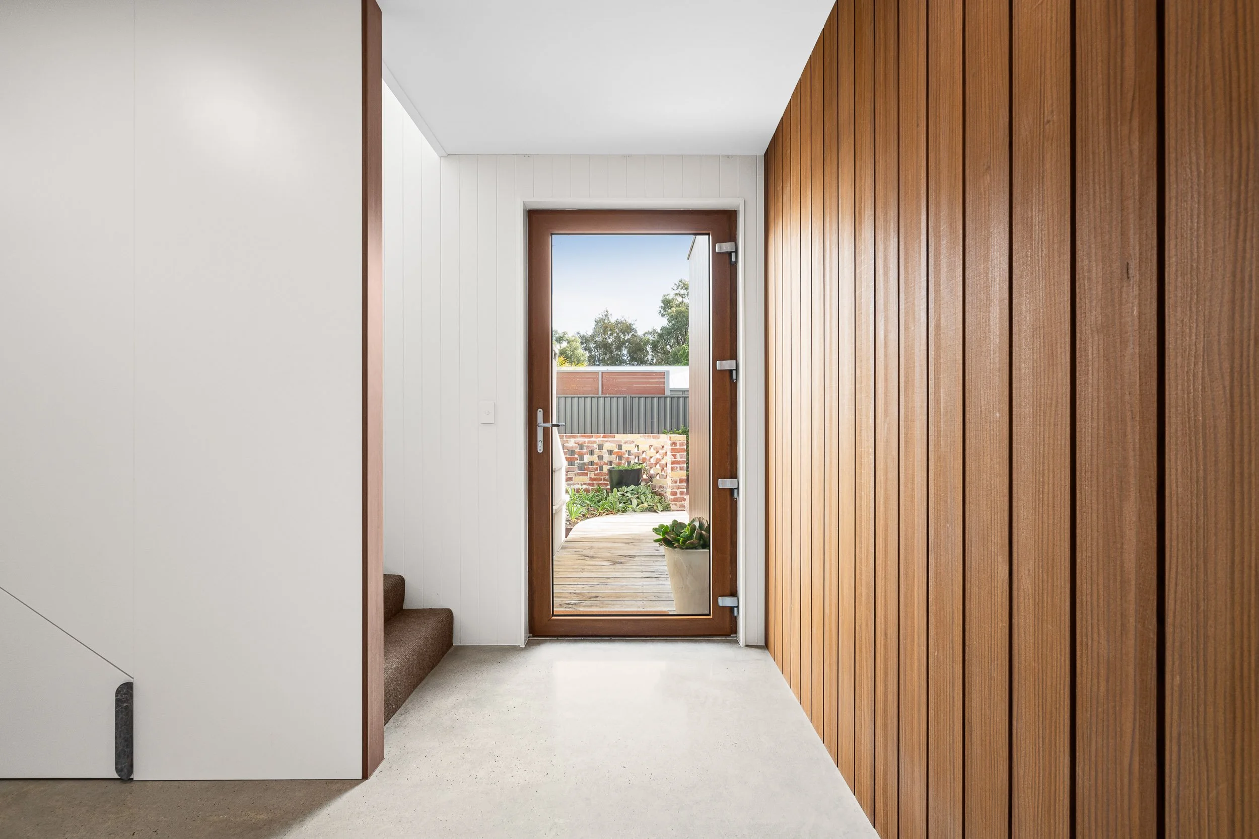 Light-filled hallway with full-height timber cabinetry and a glazed door to the garden.