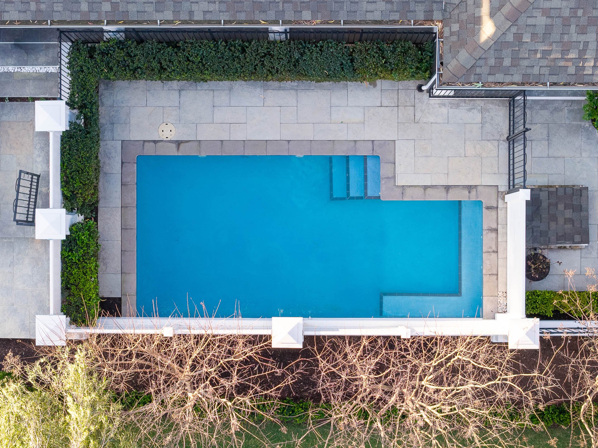 Direct overhead view of a rectangular swimming pool, surrounding paving and garden planting.
