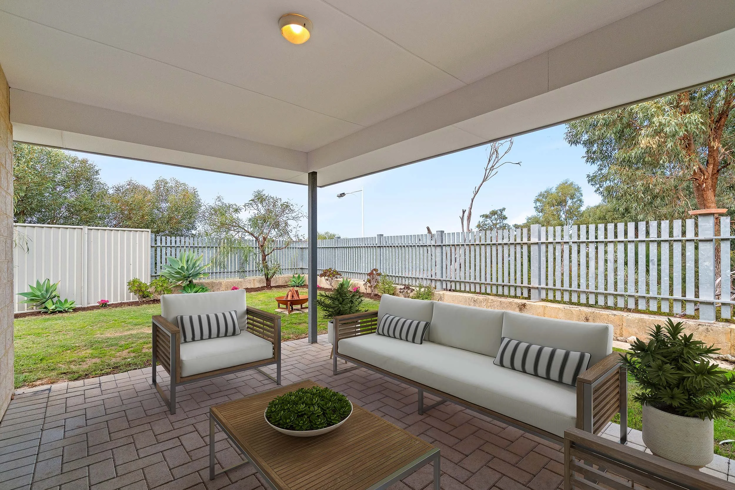 Virtually staged covered balcony with outdoor sofas, a coffee table and leafy views.